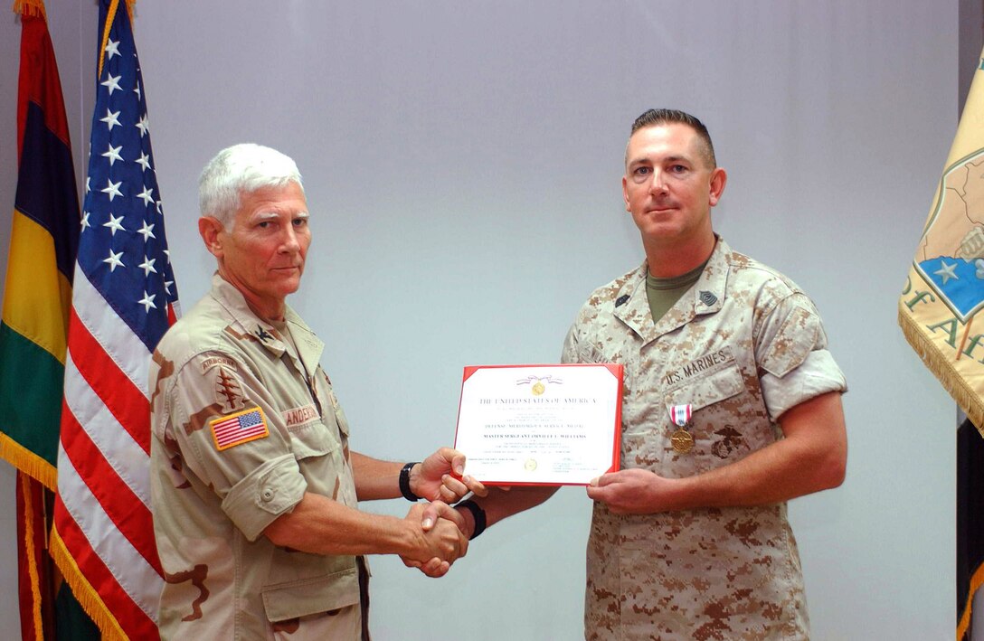 Army Col. Edwin W. Anderson, CJ-3 director, congratulates Master Sgt. Orville L. Williams, CJ-3 operations chief, after presenting him with a Defense Meritorious Service Medal recently.  Williams received the medal for outstanding service during his nine-month deployment to the Horn of Africa as a member of the Combined Joint Task Force.