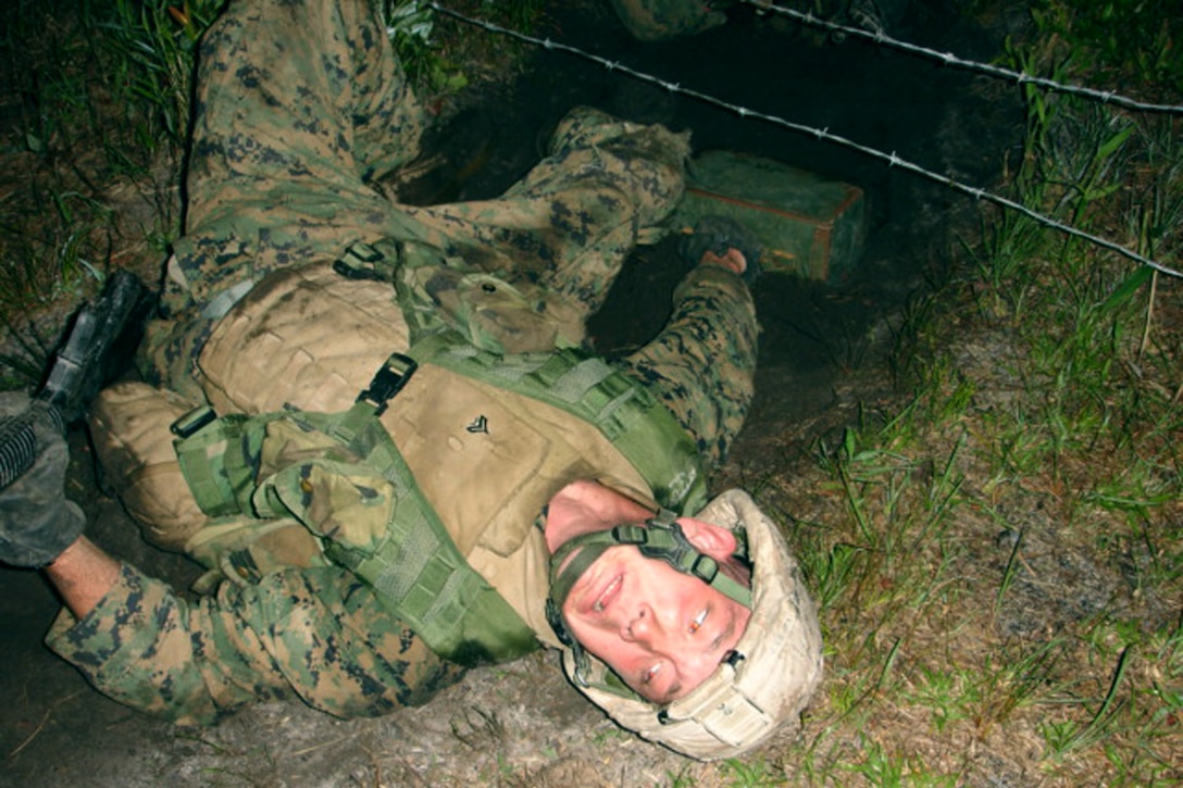 MARINE CORPS BASE CAMP LEJEUNE, N.C. - As part of the night infiltration course, a Marine drags an ammunition can under some barbed wire, being careful not to get snagged himself.  Thirty-four Marines from class 2-05 graduated the Sappers Leadership course here June 3.