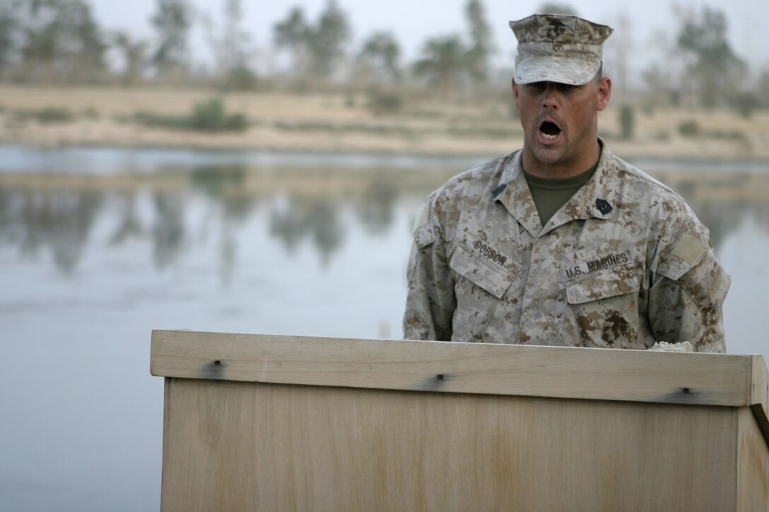 CAMP BAHARIA, Iraq - 1st Sgt Alex Dobson, Headquarters and Service Company, 1st Battalion, 6th Marine Regiment, company first sergeant, calls role during a memorial service here June 12 the unit held for Lance Cpl. Mario Castillo and Lance Cpl. Andrew Kilpela.  The two engineers with 2nd Platoon, Company A, 2nd Combat Engineer Battalion, passed away June 10 when an improvised explosive device detonated near their vehicle in a roadway outside Fallujah.