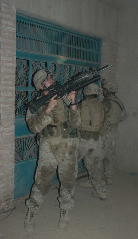 AR RAMADI Iraq (June 17, 2005) - Lance Cpl. Jim L. Cullen, a rifleman and team leader with 2nd Squad, 2nd Platoon, Company A, 1st Battalion, 5th Marine Regiment, posts security inside a building for his comrades while they attempt to breach the entrance to a room during a mission in the city here. The 21-year-old from Rochester, N.Y., and his fellow 2nd and 3rd Platoon, Company A warriors' were conducting a search mission when they were called on to provide security for a platoon of Company C Marines who hit an IED. The Marines set up lookouts on rooftops a few hundred yards from the attack seen. They remained in their surveillance positions for more than two hours. Photo by: Cpl. Tom Sloan