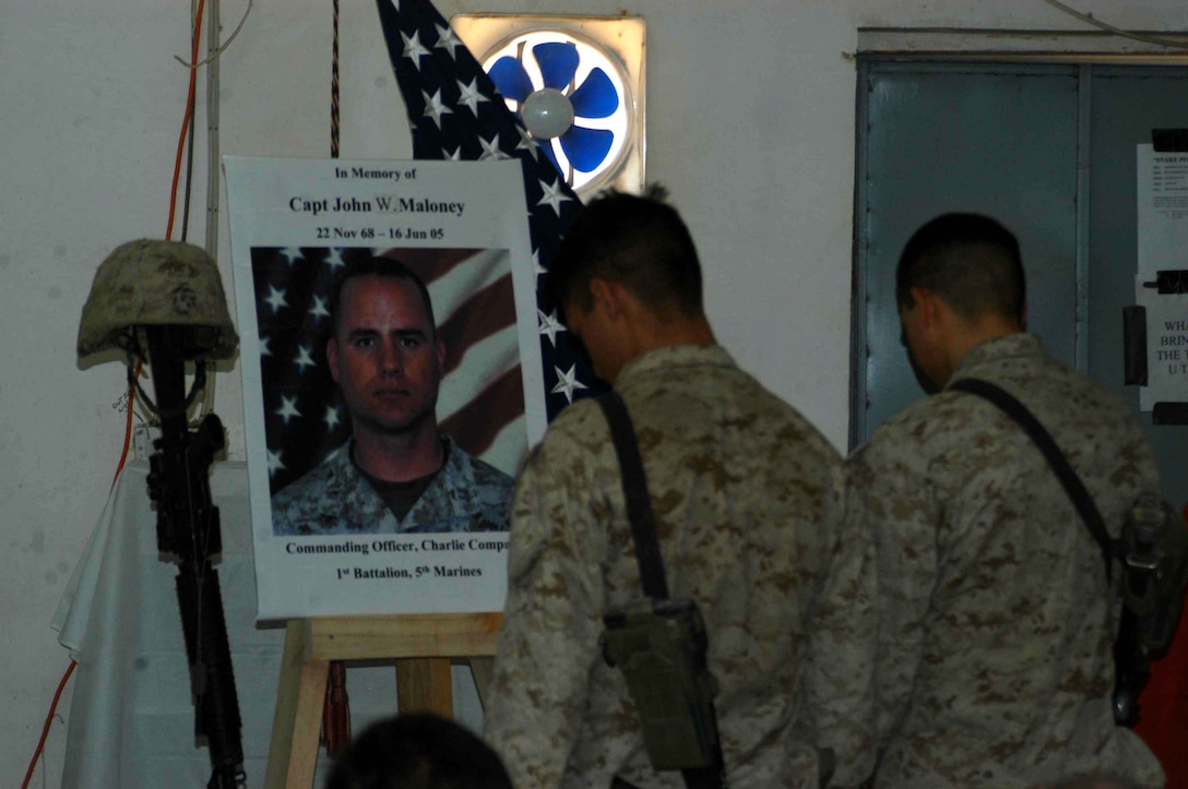 CAMP SNAKE PIT Ar Ramadi, Iraq (June 22, 2005) - Two Marines with Company C, 1st Battalion, 5th Marine Regiment, stand in front of Capt. John W. Maloney's memorial and mourn his loss during a ceremony here June 22. Maloney, a 37-year-old from Chicopee, Mass., and the late leader of Company C, was killed fighting terror in the city the evening of June 16 when an improvised explosive device exploded directly underneath his Humvee. Maloney was prior enlisted and had 18 years of dedicated service the Marine Corps under his belt when he paid the ultimate price. He's survived by his wife, Michelle, and two children, Nathaniel and McKenna. Photo by: Cpl. Tom Sloan
