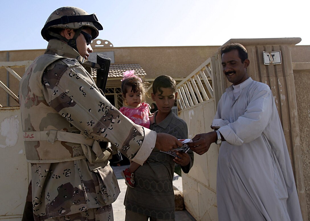 Hit, Al Anbar, Iraq (August 6, 2005)--An IIF soldiers hands out handbills during a patrol. (Official USMC Photo by Corporal Ken Melton)