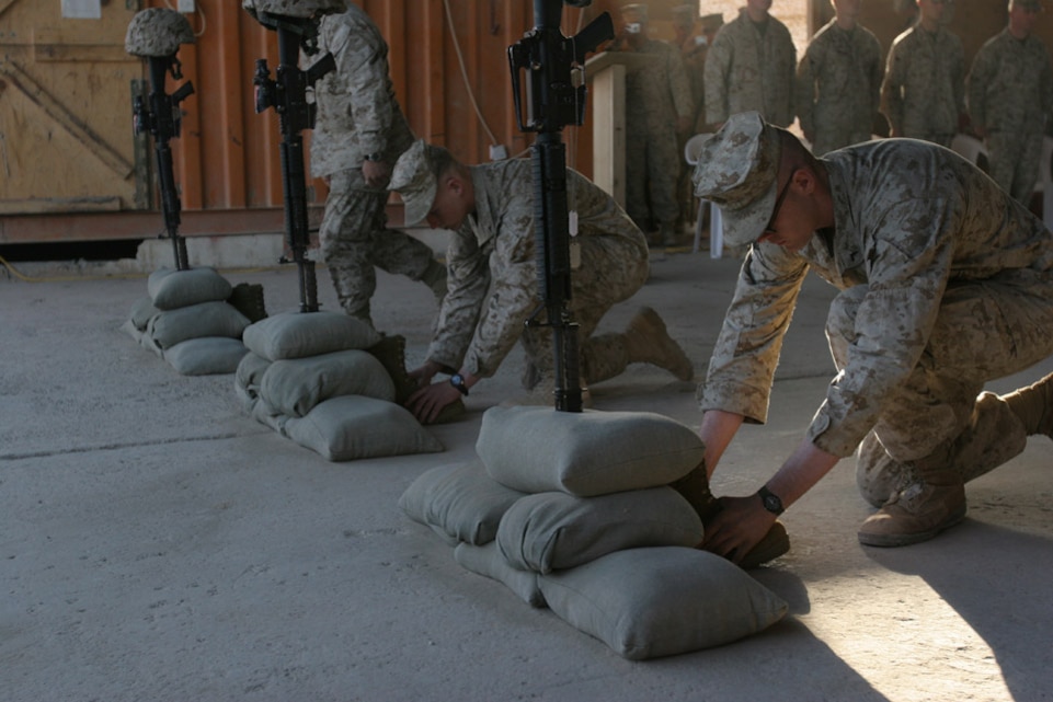051028-M-2607O-003 - Marines from Weapons Company place boots at the base of the sand bags and down turned rifles as part of the memorial emblem for the fallen Marines that died on Oct. 20, helping to make Iraq a free country.
