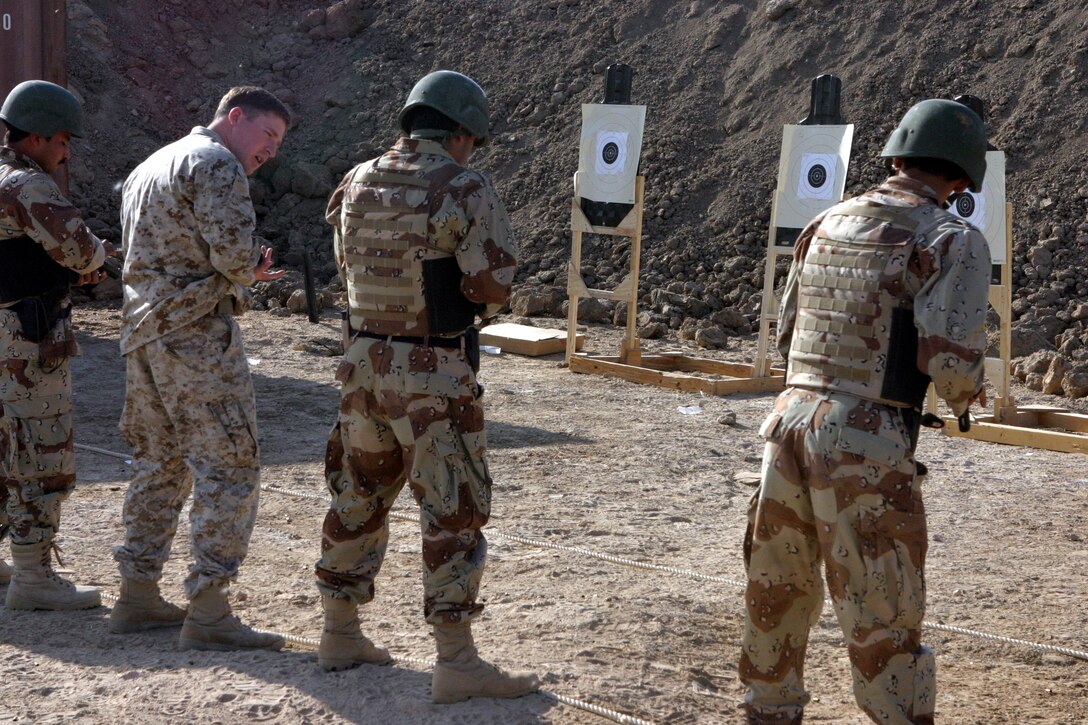 CAMP HABBANIYAH, Iraq - Corporal Seth Charles Cantrell, a weapons instructor for Personal Security Detail Development course, demonstrates to an Iraqi Soldier how to check to ensure a round is in the camber of his pistol.