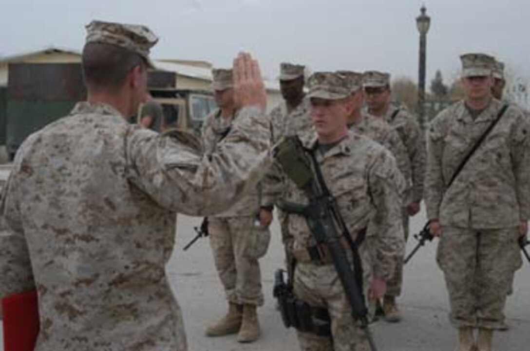 HURRICANE POINT, Ramadi, Iraq  -- Staff Sgt. Robert D. Oehler, intelligence chief for Headquarters and Service Company, 1st Battalion, 5th Marine Regiment, holds up his right hand and repeats after his commanding officer, Lt. Col. Eric M. Smith of Plano, Texas, during his reenlistment ceremony here March 6, 2005. The 28-year-old Jacksonville, Fla. Native, a Marine with almost a decade of dedicated service to the Corps, swore to devote another four years while in Iraq a second time in support of Operation Iraqi Freedom. Oehler collected a bonus of more than $10,000 that's tax-free because he reenlisted in Iraq, which the Department of Defense designated to be a tax-exclusion zone.                                 (Official United States Marine Corps photo by Cpl. Tom Sloan)