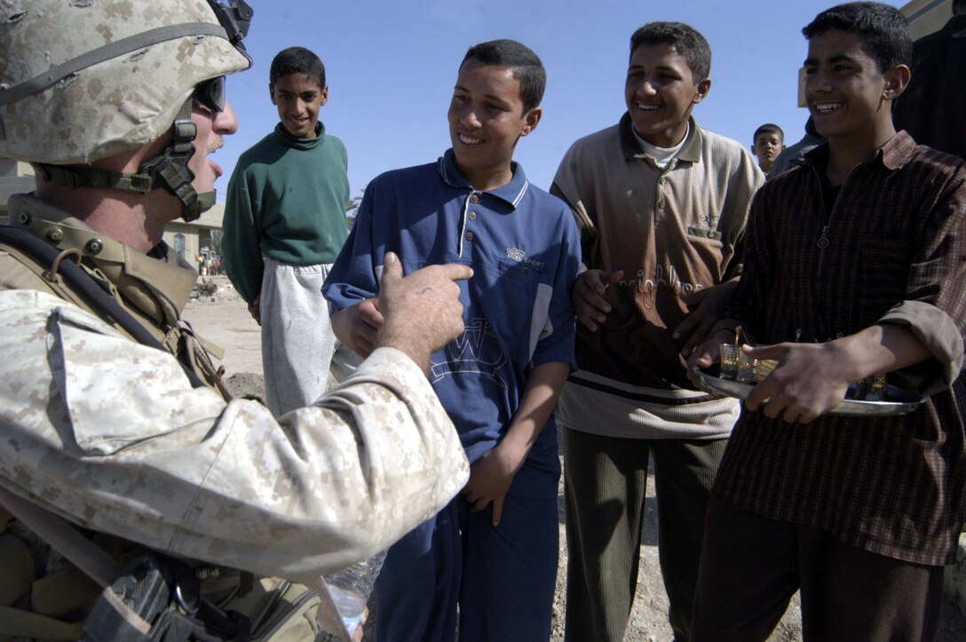 Halabisah, IRAQ - One of 3rd Battalion, 4th Marines, Regimental Combat Team-1's riflemen, Corporal Paul B. Worley, 25-year-old native of Eden, N.C., laughs with Iraqi children after sharing hot tea and freshly baked bread in Halabisah, Iraq during Operation Peninsula Plague March 1. Marines uncovered multiple weapons caches and captured 18 members of anti-Iraqi forces, without any enemy contact while conducting the 72-hour operation.