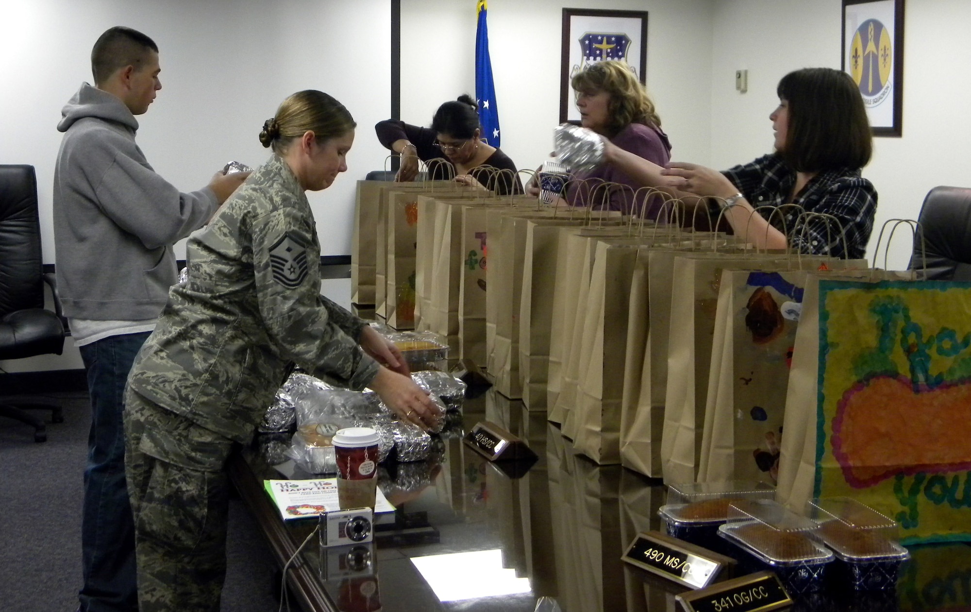 Master Sgt. Sheila Lawson, foreground, first sergeant for the 341st Operations Group, works with family members from her squadron to pack goodie bags Thanksgiving morning. Several spouses made homemade breads and the children at the youth center decorated the bags that were distributed to the missile crews deploying to the complex that morning. (U.S. Air Force courtesy photo)