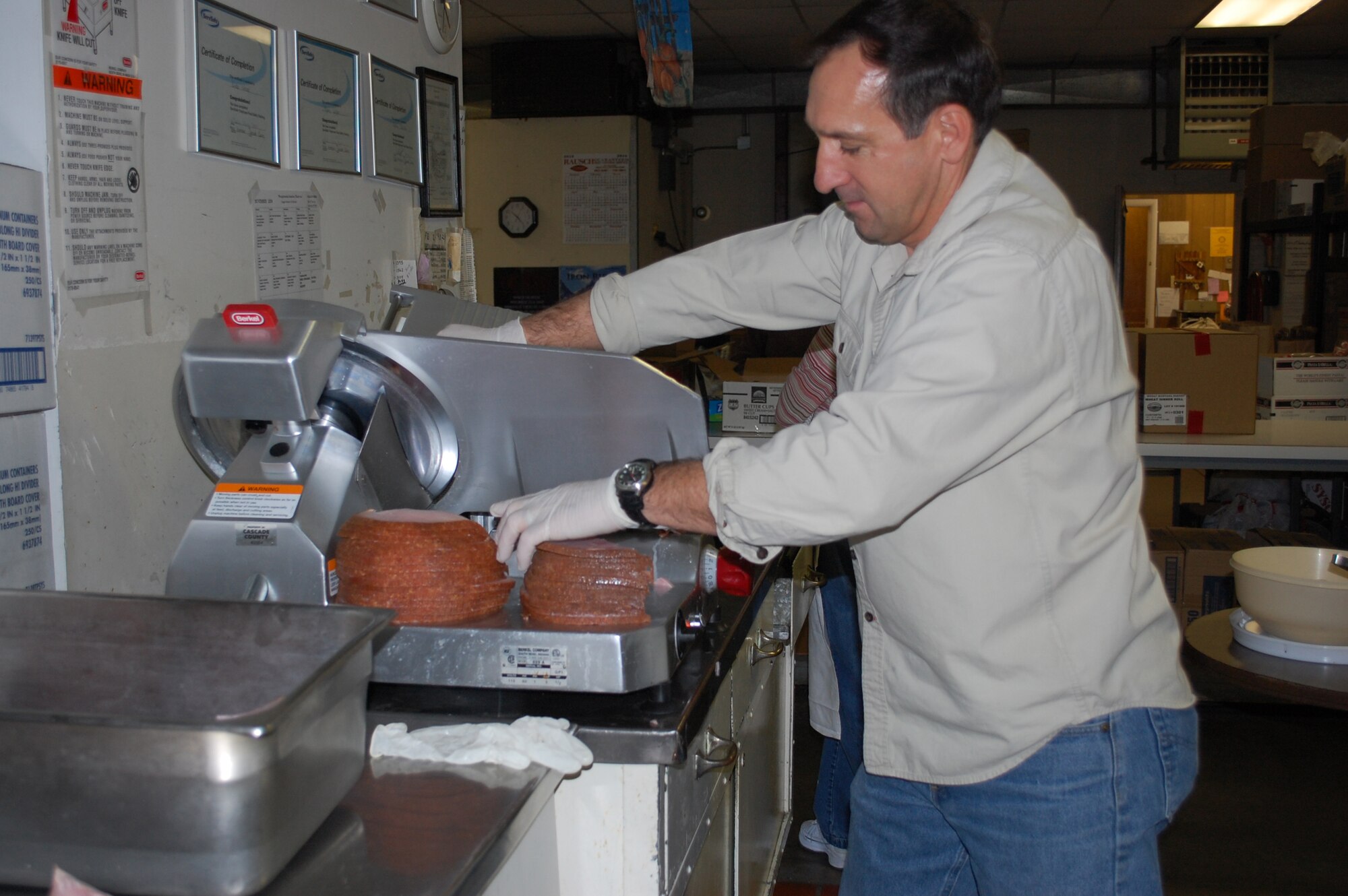 Brian Jolly, Chief of the Manpower and Personnel Flight for the 341st Force Support Squadron, slices hams at the Meals-on-Wheels kitchen Nov. 25. Ham was also included in the Thanksgiving day meals prepared for delivery to local area seniors. Volunteers from Malmstrom did all the pre-preparation, packaging, deliveries and clean-up so that the regular Meals-on-Wheels drivers could spend the day with their families. (U.S. Air Force photo/Valerie Mullett)