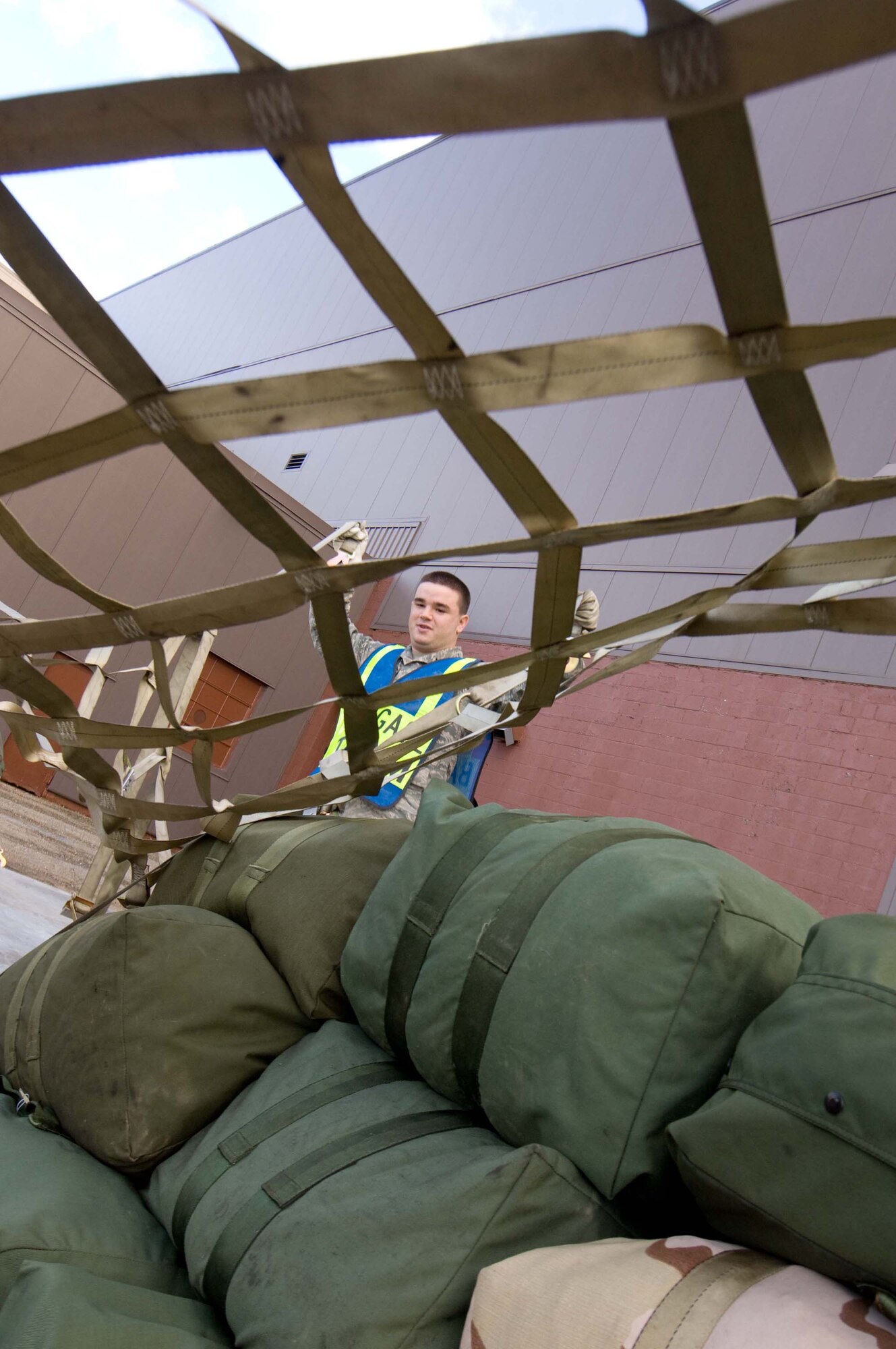 LANGLEY AIR FORCE BASE, Va. -- Airman 1st Class James Pirner, Baggage Team member, pulls a cargo net over a pallet during a Phase I Operational Readiness Exercise Dec. 3. Wing Exercise Evaluation Team members will assess the ability of 1st Fighter Wing units to deploy cargo, aircraft and Airmen within a limited timeframe. (U.S.  Air Force photo/Staff Sgt. Barry Loo)