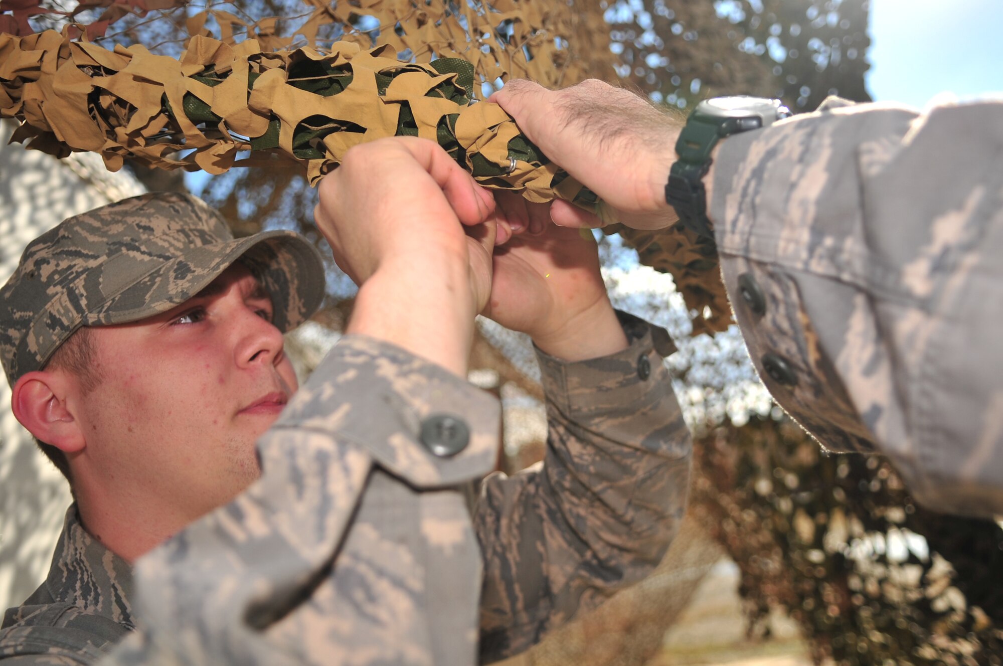 Airman 1st Class Michael Garrison, 4th Security Force Squadron security response team member, zip-ties camouflage netting in preparation for a Phase II operational readiness exercise on Seymour Johnson Air Force Base, N.C., Dec. 3, 2009. The camouflage netting makes it more difficult for enemies to identify buildings and vehicles. Airman Garrison hails from Greenville, N.C. (U.S. Air Force photo/Airman 1st Class Rae Perry)