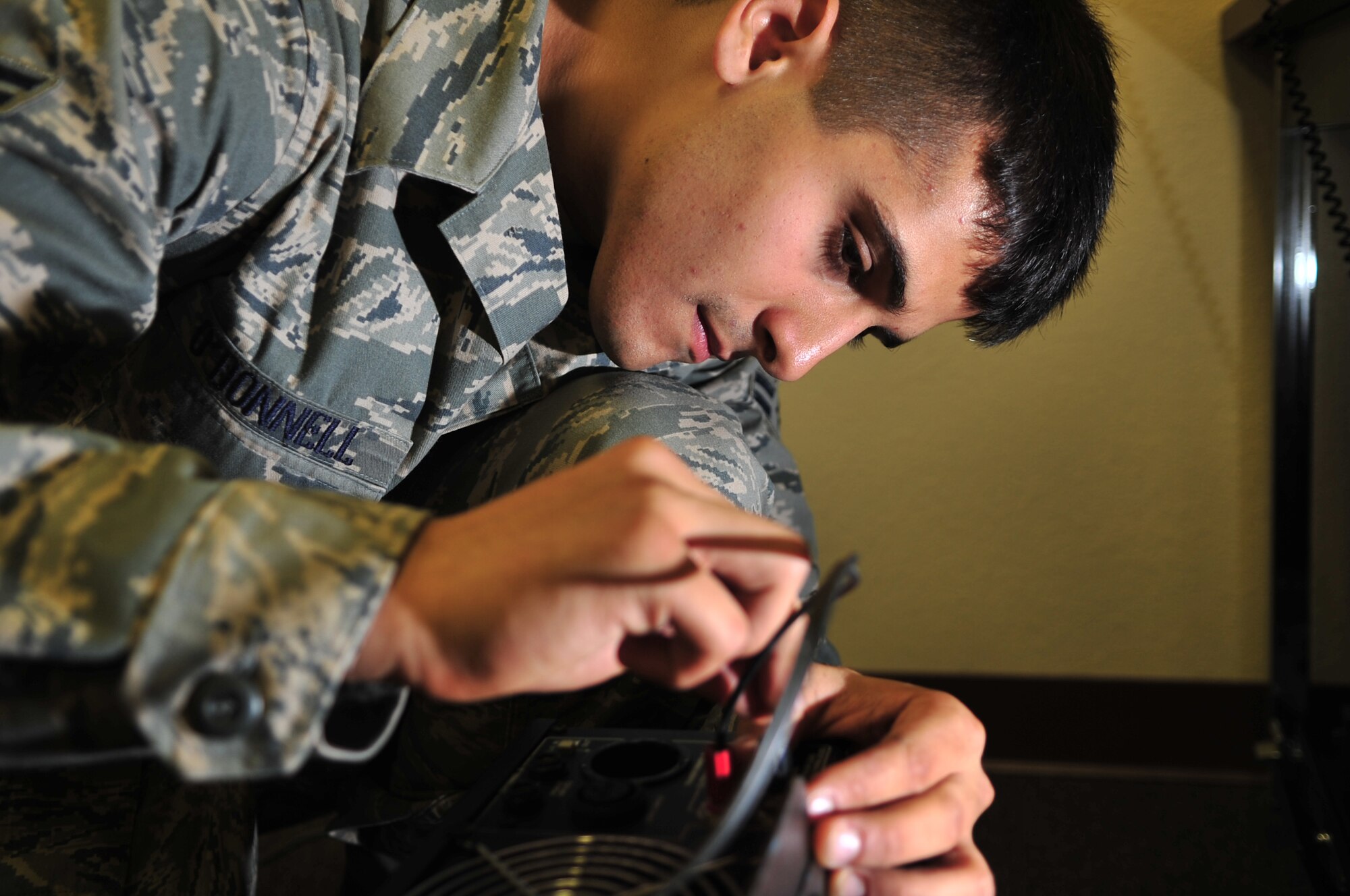 Airman 1st Class Ross O'Donnell, 4th Communications Squadron transmission systems technician, inserts positive and negative leads into an amplifier for the giant voice system on Seymour Johnson Air Force Base, N.C., Dec. 3, 2009. The amplifier is used to relay messages to Airmen in Base X during the Phase II operational readiness exercise. Airman O'Donnell hails from Fishers, Ind. (U.S. Air Force photo/Airman 1st Class Rae Perry)