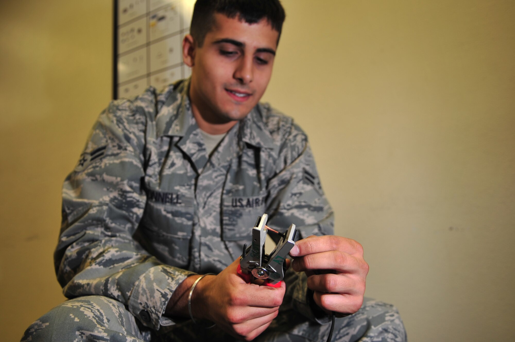 Airman 1st Class Ross O'Donnell, 4th Communications Squadron transmission systems technician, removes coating from a copper speaker wire on Seymour Johnson Air Force Base, N.C., Dec. 3, 2009. The wire connects speakers to the giant voice system used for the upcoming a Phase II operational readiness exercise. Airman O'Donnell hails from Fishers, Ind. (U.S. Air Force photo/Airman 1st Class Rae Perry)