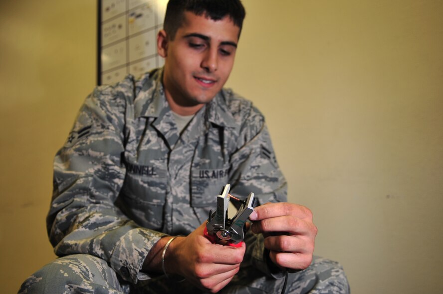 Airman 1st Class Ross O'Donnell, 4th Communications Squadron transmission systems technician, removes coating from a copper speaker wire on Seymour Johnson Air Force Base, N.C., Dec. 3, 2009. The wire connects speakers to the giant voice system used for the upcoming a Phase II operational readiness exercise. Airman O'Donnell hails from Fishers, Ind. (U.S. Air Force photo/Airman 1st Class Rae Perry)