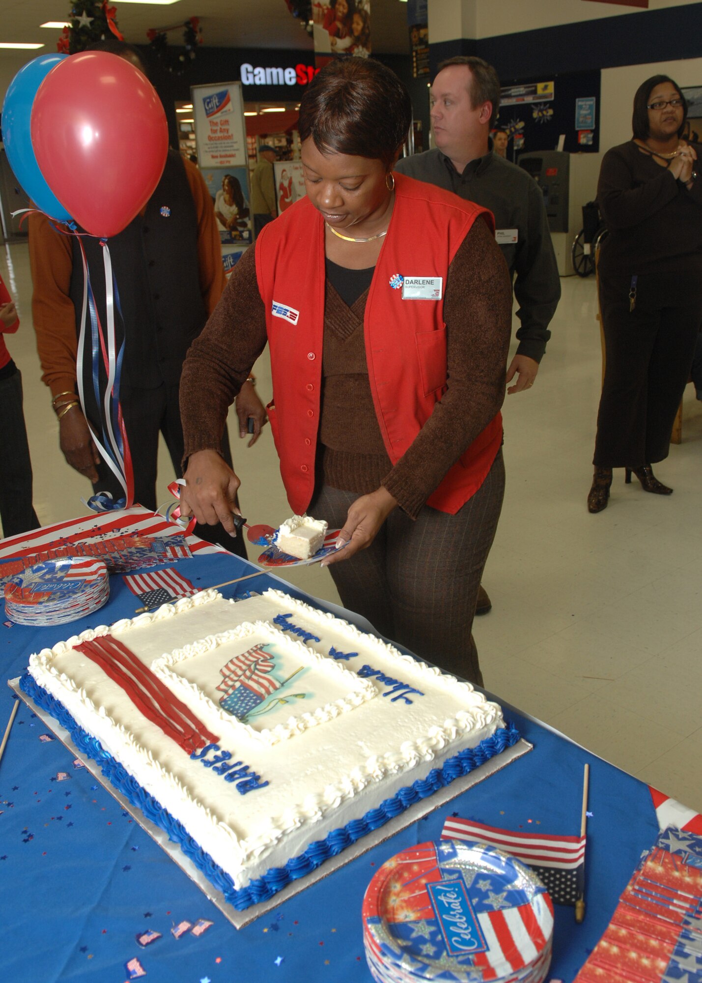 Darlene Downing, cuts a cake during her welcome home ceremony at the Barksdale base exchange Dec. 1.  Ms. Downing recently returned from a 14-month deployment in Afghanistan.  She said she extended her initial six month deployment twice to be able to give back to servicemembers and to do her part of AAFES slogan, “We go where you go.”  (U.S. Air Force photo by Staff Sgt. Sarah E. Stegman)