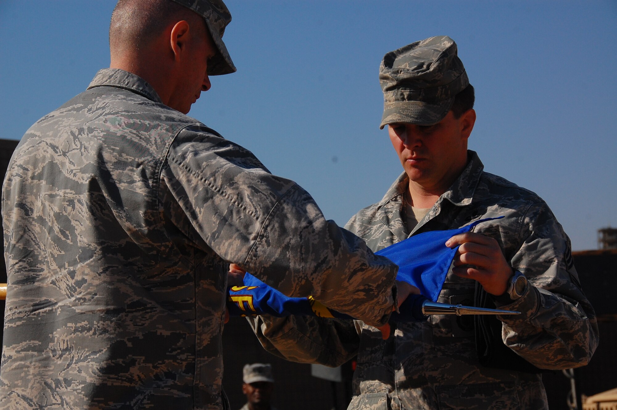 CAMP BUCCA, Iraq -- Maj. Larry Wood, 887th Expeditionary Security Forces Squadron commander, left, and Chief Master Sgt. James Johnson, furl the 887th ESFS guidon during the squadron’s deactivation ceremony Dec. 3.  (U.S. Air Force photo/Staff Sgt. Shaun Emery)