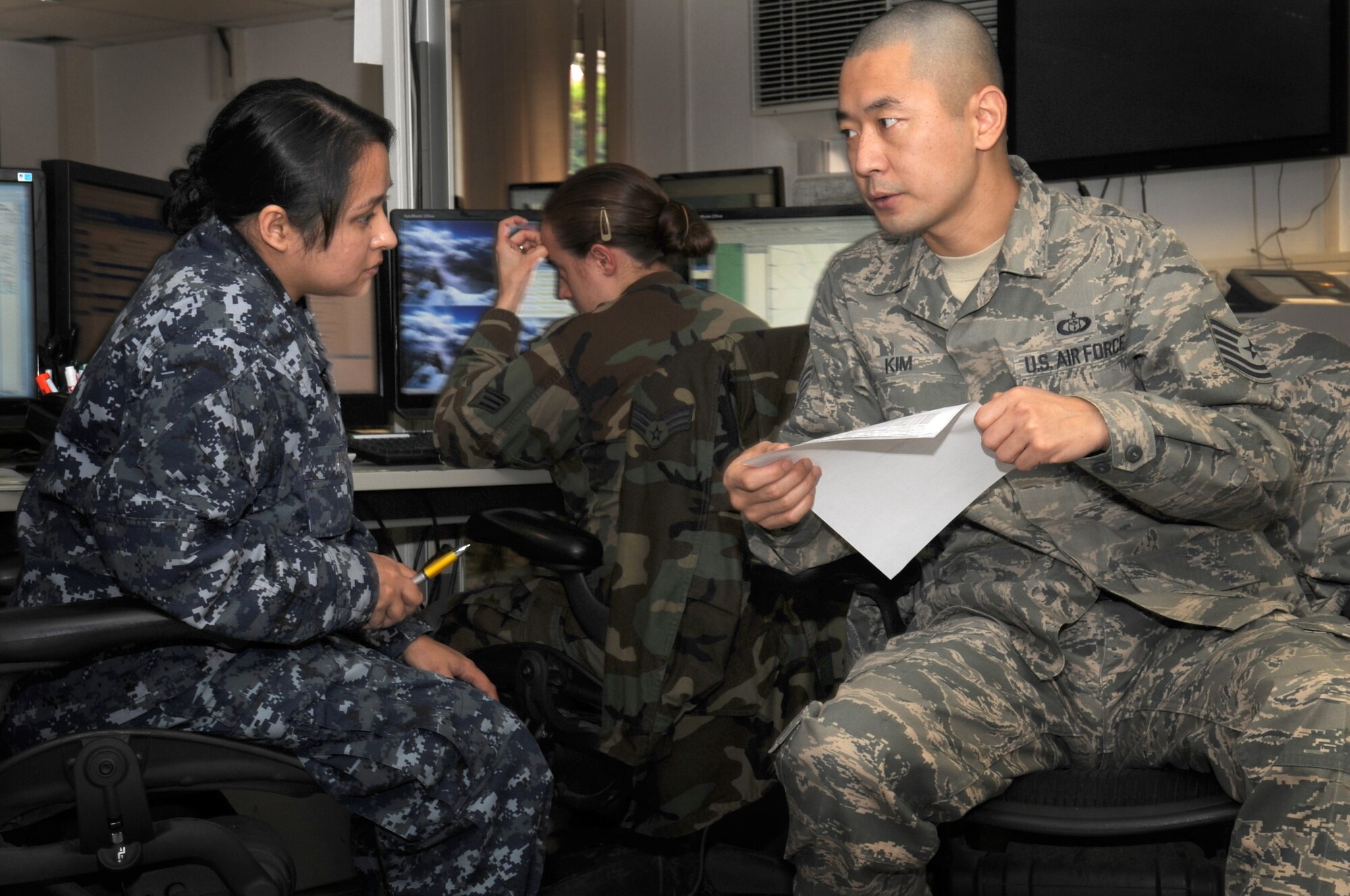 U.S. Navy Aerographers Mate, Petty Officer 2nd Class Susana Awan discuses collected weather information with U.S. Air Force Technical Sgt. Yong Kim in order to relay a weather hazard to pilots in flight on Dec 3, 2009.  Awan and Kim work together at the 21st Weather Squadron, Sembach Annex, Germany.  (U.S. Air Force Photo by Staff Sgt. Jocelyn Rich)
