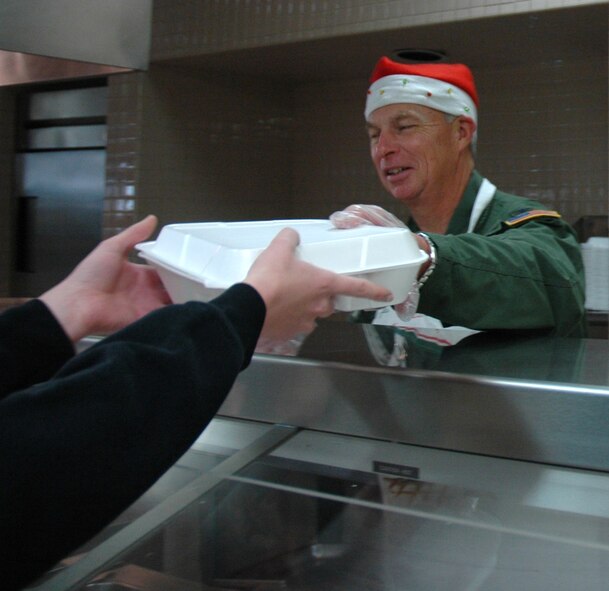 MCCHORD AIR FORCE BASE, Wash.- Col. William Flanigan, 446th Airlift Wing commander here, helps serve lunch at the serving line at the Olympic Dining Facility here during the December Reserve weekend. Major Lee is one of many officers and senior enlisted Reservists who took part in serving meals to show members from the wing their appreciation for all of the hard work and dedication they bring throughout the year. (U.S. Air Force photo/Master Sgt. Jake Chappelle)