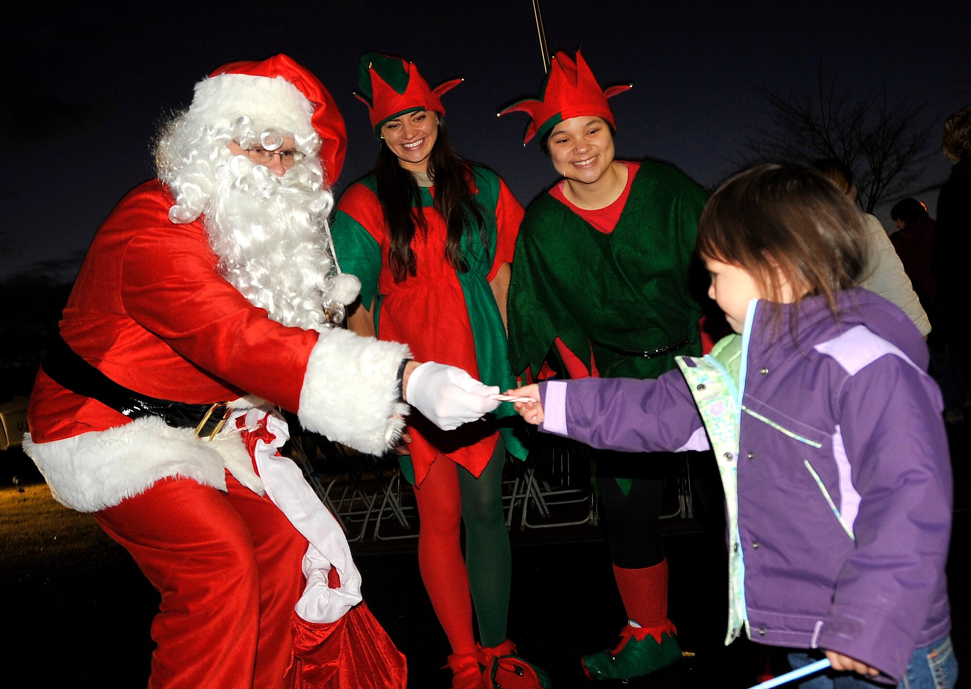 MISAWA AIR BASE, Japan -- Santa Claus and his two elves give candy to Jayelin Alexander, daughter of Staff Sgt. Angel Alexander, 35th Civil Engineer Squadron heating, ventilation and air conditioning craftsman, during the annual Tree Lighting Ceremony Dec. 4 at Risner Circle. Spectators of the event were able to treat themselves to hot chocolate while they enjoyed live entertainment. (U.S. Air Force photo/Staff Sgt. Chad C. Strohmeyer)
