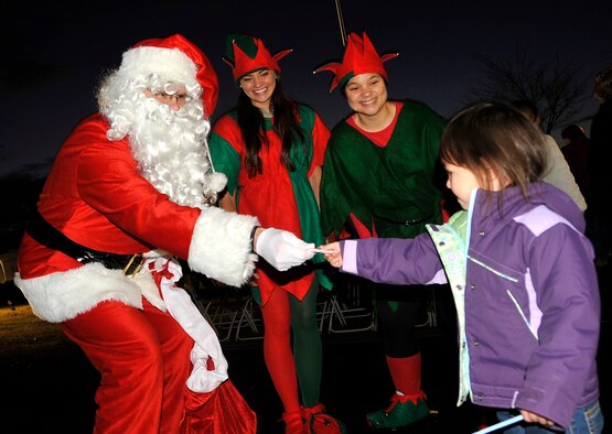 MISAWA AIR BASE, Japan -- Santa Claus and his two elves give candy to Jayelin Alexander, daughter of Staff Sgt. Angel Alexander, 35th Civil Engineer Squadron heating, ventilation and air conditioning craftsman, during the annual Tree Lighting Ceremony Dec. 4 at Risner Circle. Spectators of the event were able to treat themselves to hot chocolate while they enjoyed live entertainment. (U.S. Air Force photo/Staff Sgt. Chad C. Strohmeyer)