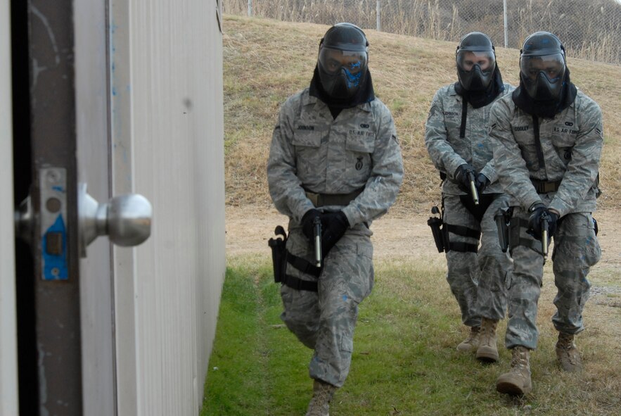 KUNSAN AIR BASE, Republic of Korea -- The team of Airman Antonio Johnson, Staff Sgt. Jeremy Johnson, and Airman 1st Class Tyrone Cooley, all with the 8th Security Forces Squadron, advances towards the door of a building with armed suspects during simulated rounds training here Dec. 2. The Simulated rounds training taught new Security Forces members proper ways to clear a building by engaging them with various situations. These trainees faced various situations that included both armed and unarmed suspects inside of a building. (U.S. Air Force photo/Staff Sgt. Darnell T. Cannady)