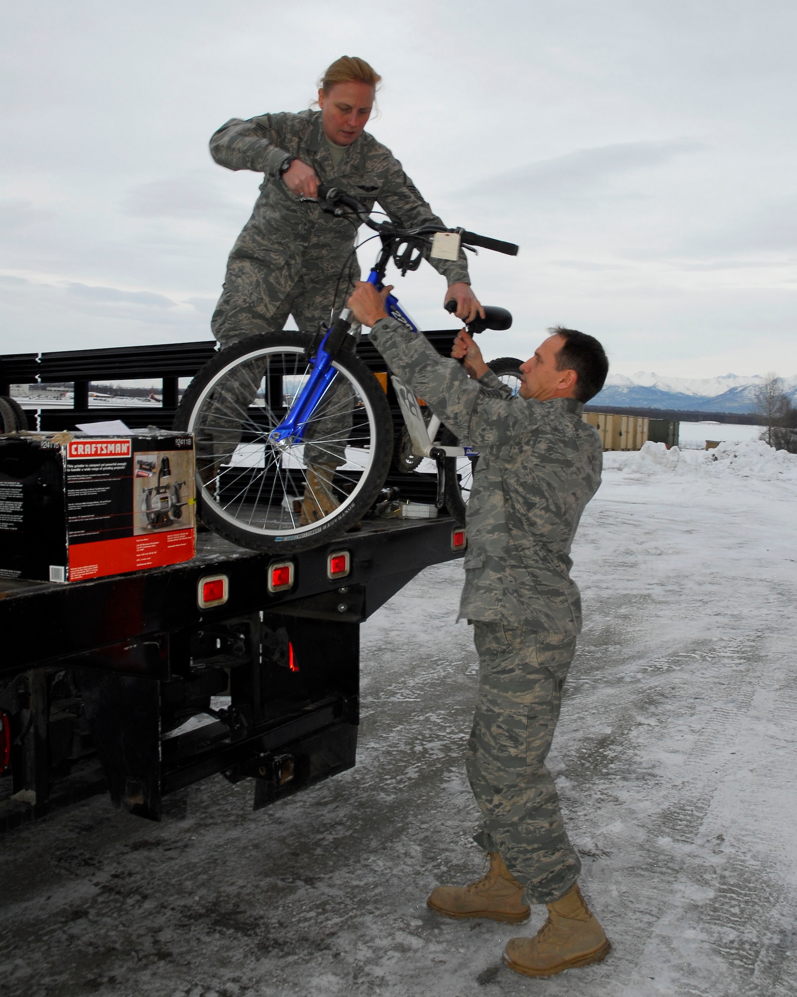 Alaska Air Guardsman Master Sgt. Tess Walsh hands Senior Master Sgt. Thomas Martin a bicycle from the truck bed on December 5, 2009. Walsh and Martin are from the 176th Logistics Readiness Squadron, Alaska Air National Guard, Anchorage, Alaska. The bicycle and twenty-two other refurbished bikes will be airlifted by the Alaska Air National Guard?s144th Airlift Squadron, to Afghanistan to be given to disadvantaged children. (Alaska Air National Guard photo by Tech. Sgt. Shannon Oleson)