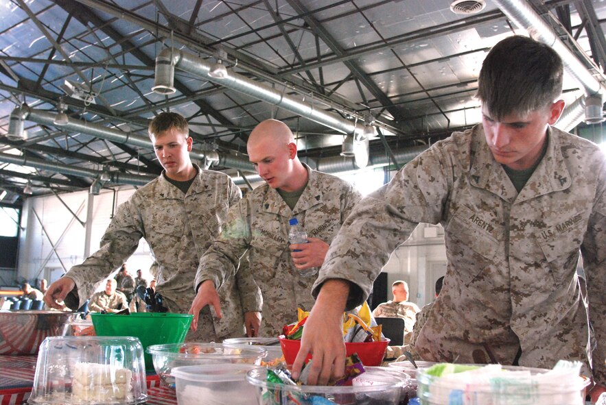 Three Marines choose snacks from the well-stocked food table and peanut butter and jelly sandwich station at the March deployment hangar.  Volunteers encourage deploying service members to take a few snacks along for the plane ride, too.  (U.S. Air Force photo by Megan Just)