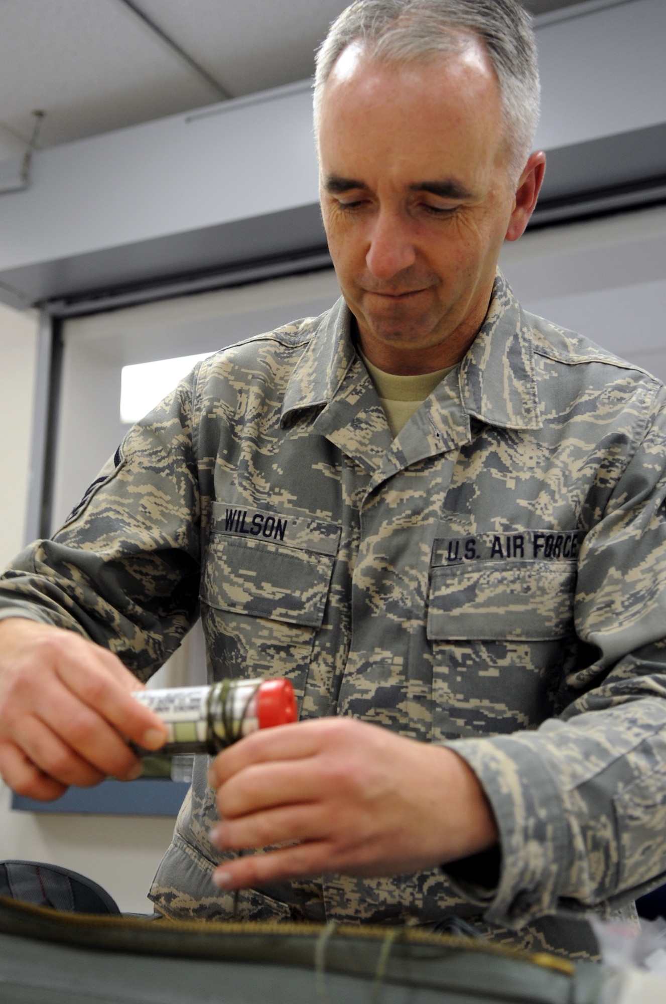 MSgt. Tim Wilson wraps safety strings around items that are packed into the survival kits so that they don't get lost when the bag is open. (Photo by Senior Airman Cory Todd/USAF 509th BW)
