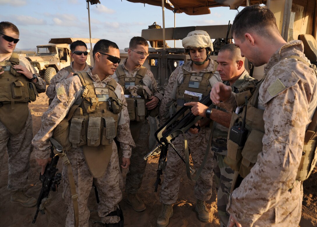 A Legionnaire with the 13th Demi-Brigade of the French Foreign Legion shows his weapon to members of Company E, Battalion Landing Team 2/4, 11th Marine Expeditionary Unit, here Dec. 6. The Marines trained with the French military unit Dec. 4-10 at numerous locations here.