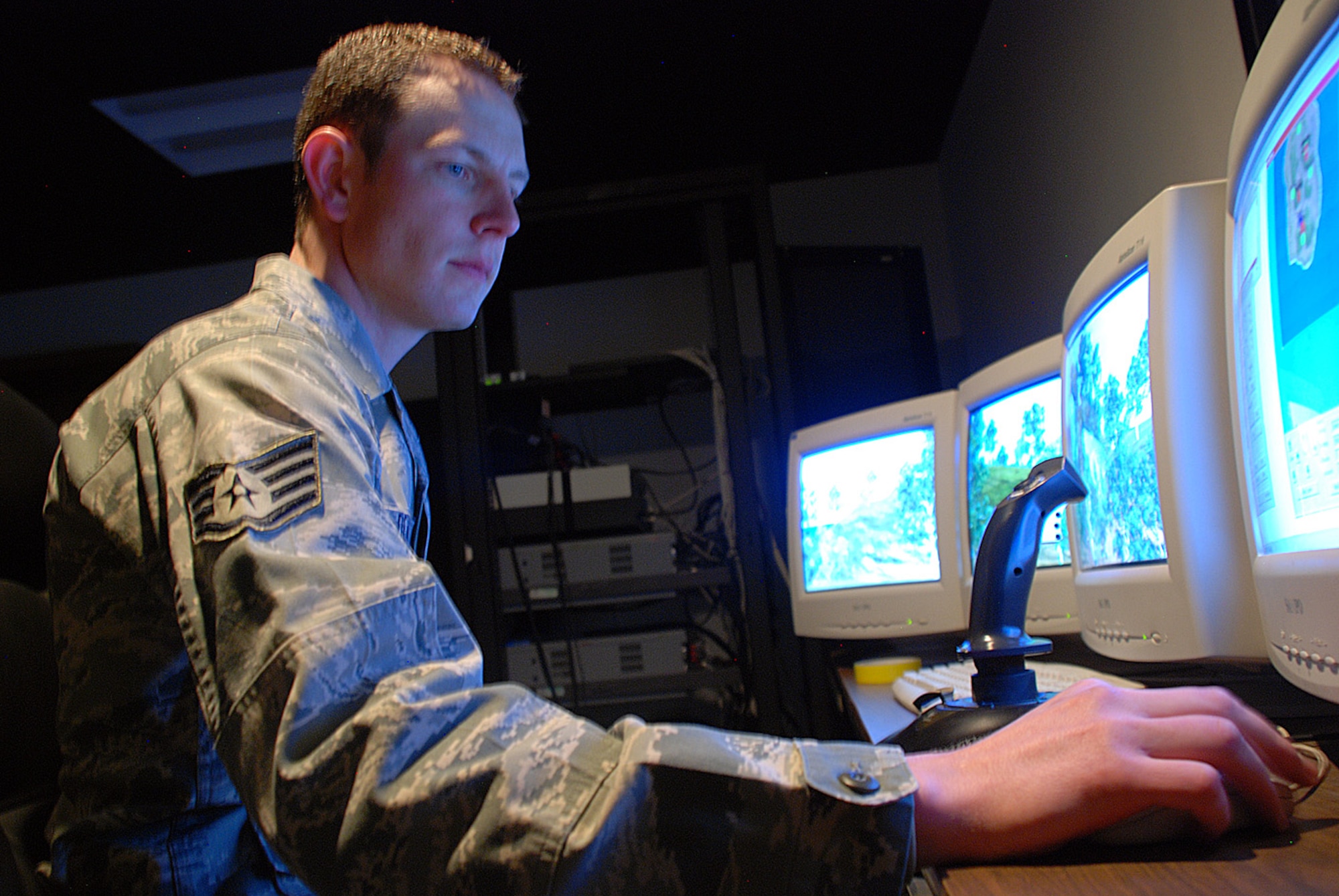Staff Sgt. Tim DeWitt Jr., 90th Security Support Squadron, controls the camera and operating system of the firearm training simulator during a March 10 training session. Security forces Airmen are required to take weapons familiarization courses at least once per three months. The program Sergeant DeWitt uses broadcasts upon a large screen, and he controls what the training Airmen see. Using a joystick, the sergeant navigates toward a crown of partially hidden enemies. The training Airmen then fire their mock weapons toward the screen, where the program registers accuracy. At the end of the session, points are tallied as to how many fake bullets were fired and how many digital enemies were killed. (U.S. Air Force photos by Senior Airman Daryl Knee) 