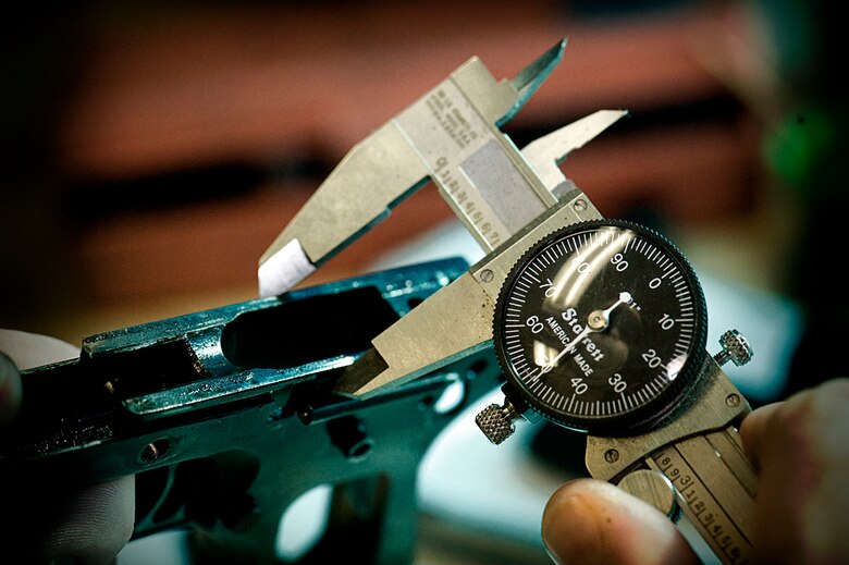 With his tools of the trade always near his side to take precision measurements and accomplish the most detailed work, William Moore can fix or refurbish just about any small arms, including this Colt 45 with a red dot optical sight (facing page) for the Air Force Shooting Team. At right is a 6-inch caliper, which provides the detail needed to ensure a gun works properly.