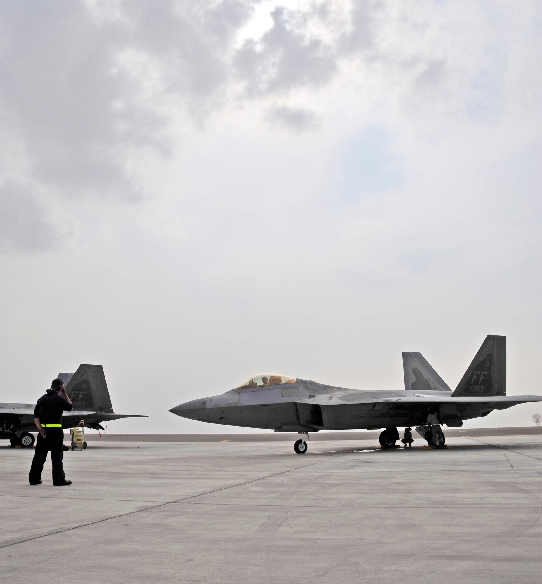 Senior Airman Adam Smith, 1st Fighter Wing crew chief, prepares to marshal an F-22 Raptor Nov. 30, 2009, at an airfield in Southwest Asia. Airman Smith is participating in the Iron Falcon exercise while on temporary duty from Langley Air Force Base, Va. Airman Smith is from Boston. (U.S. Air Force photo/Tech. Sgt. Charles Larkin Sr)