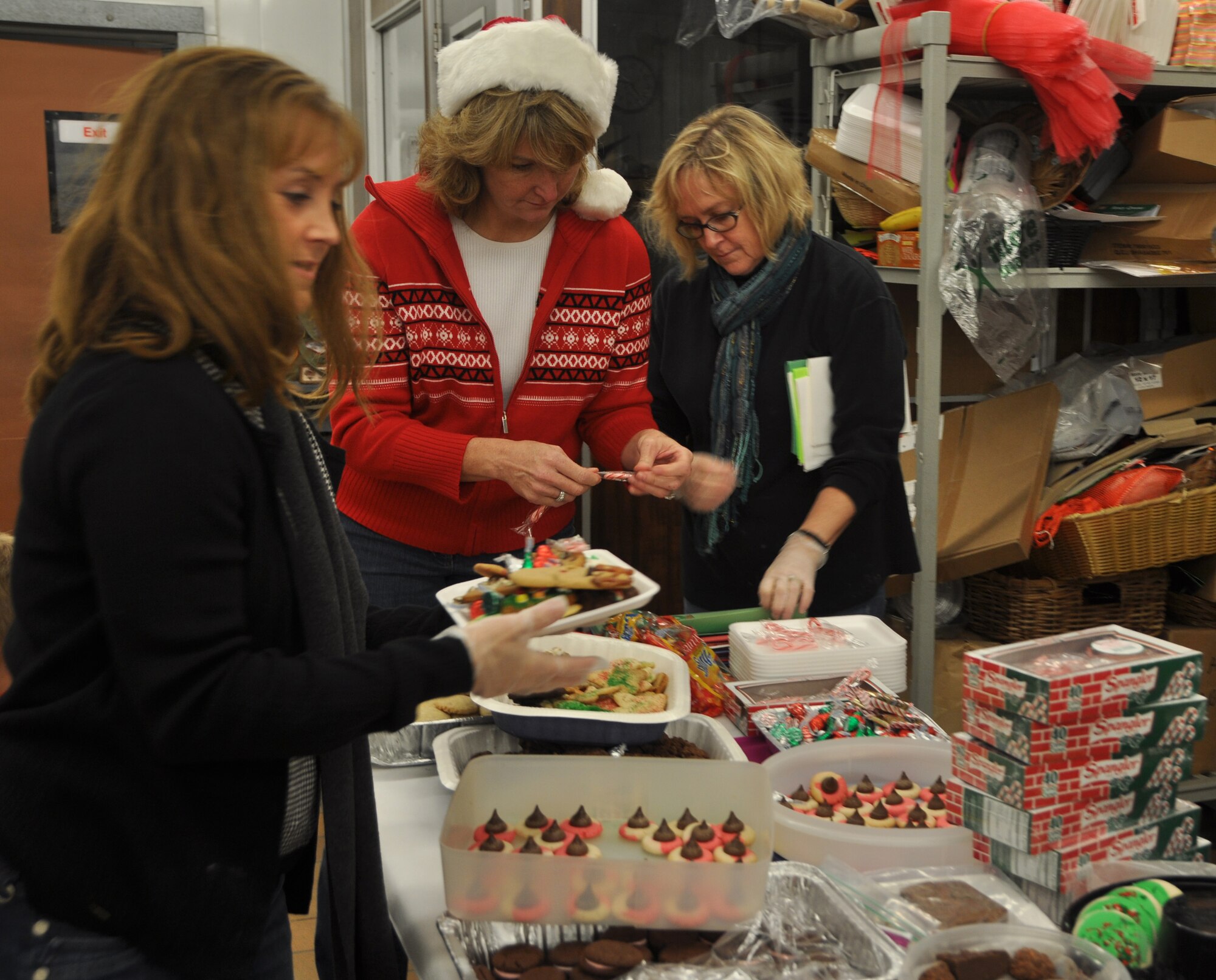 Kymble McCoy, Cheryl Roberson and Mindy Van Vleet take part in operation 'Cookie Caper' Dec. 7 at the commissary. The Officer Spouse's Club and the Enlisted Spouse's Club come together each year to make cookie plates with cards for all Tyndall dorm residents who may not see their families over the holiday season. (U.S. Air Force photo by Airman 1st Class Rachelle Elsea)
