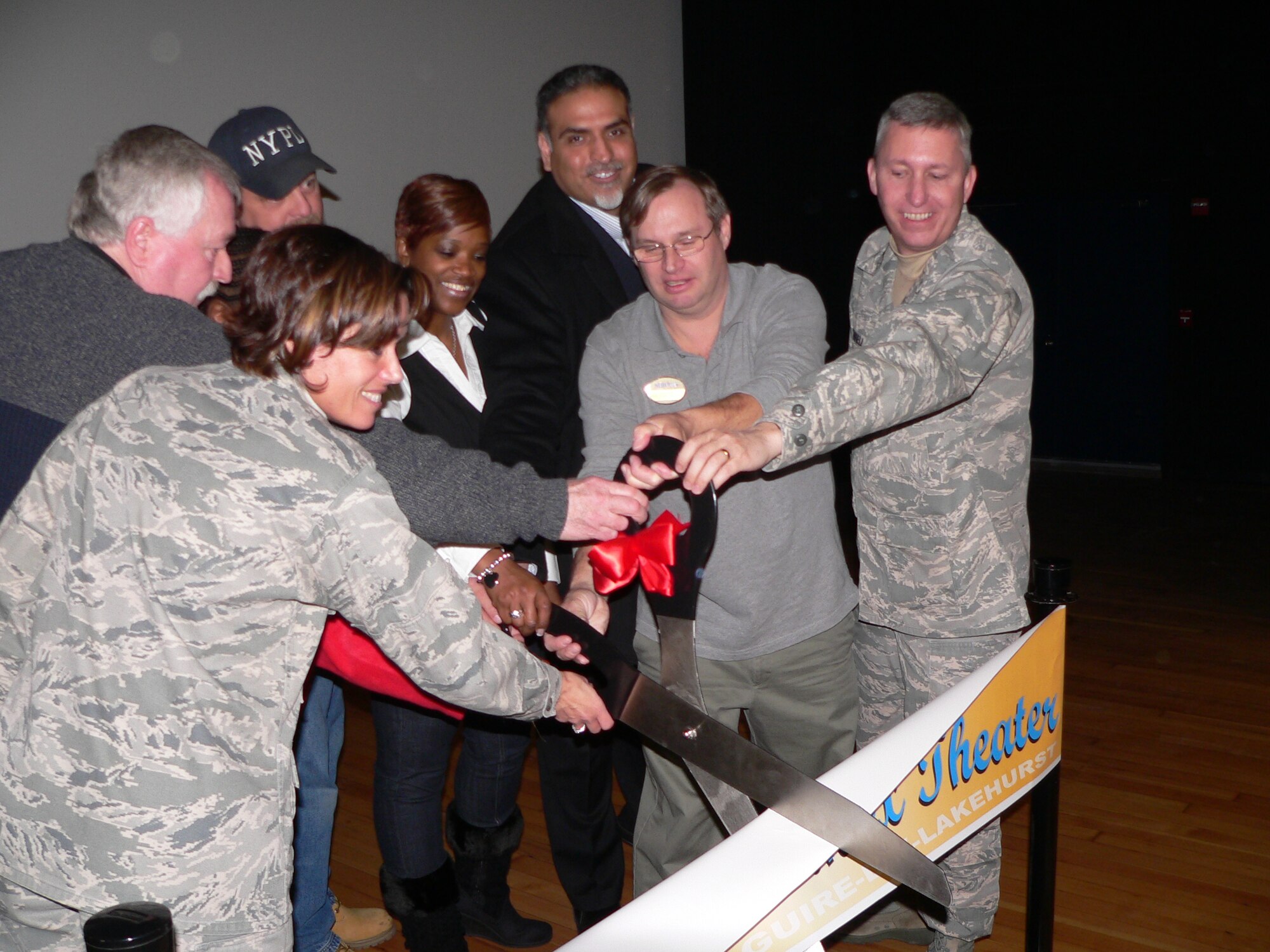 The ribbon is cut at the opening ceremony of the newly renovated McGuire Theater Dec. 6. The theatre went through a variety of changes over the past year. The theater’s exterior renovations include new walkways, ramps, underground drainage, a standing-seam metal roof and parking spaces. Fabric walls with cherry wood wainscot bases, concession cabinets, ramps and a refinished stage will be found in the newly renovated interior. (U.S. Air Force photo/Steve Snyder)