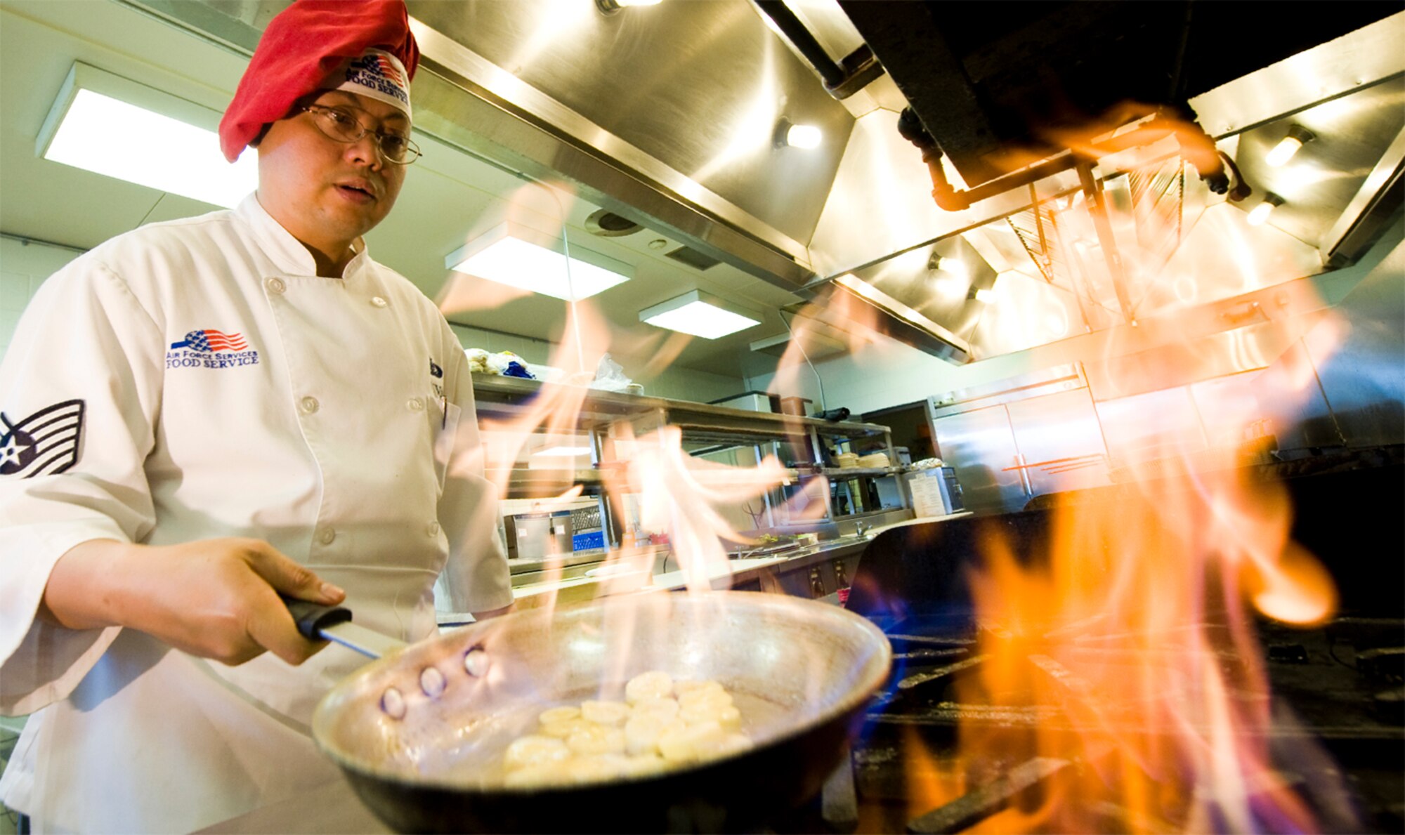 Working over a hot flaming stove is nothing new for seasoned chef Tech. Sgt. Rhodello Nuval. He says the main thing he has to guard against is complacency because he is so comfortable in the kitchen. (photo by Tech. Sgt. Matthew Hannen)