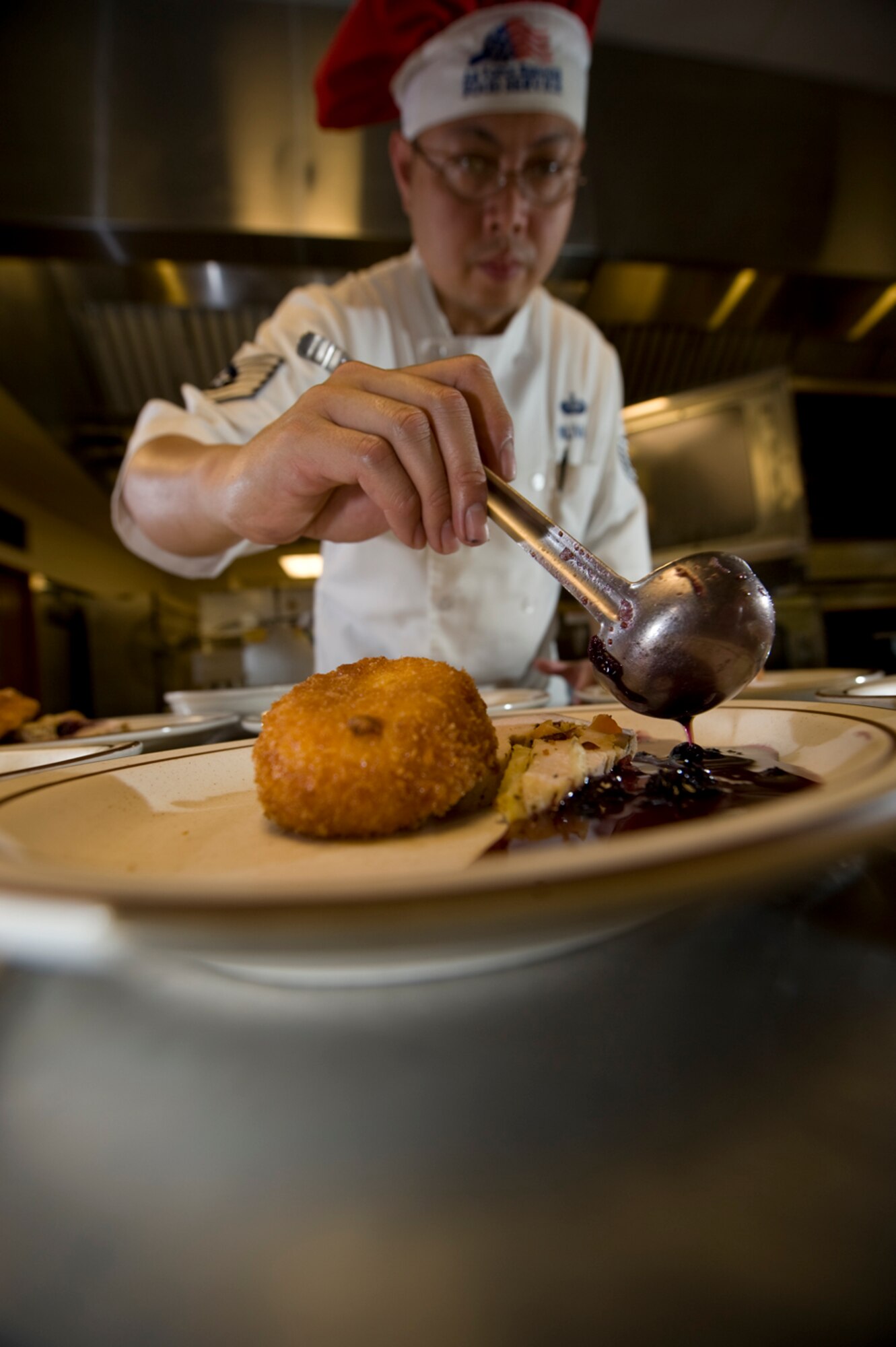 Re-creating a dish that won on the Emeril Live show, Chef Nuval makes rainbow fruit stuffed pork tenderloin and cheddar fried grits, with blueberry coulees. (photo by Tech. Sgt. Matthew Hannen)