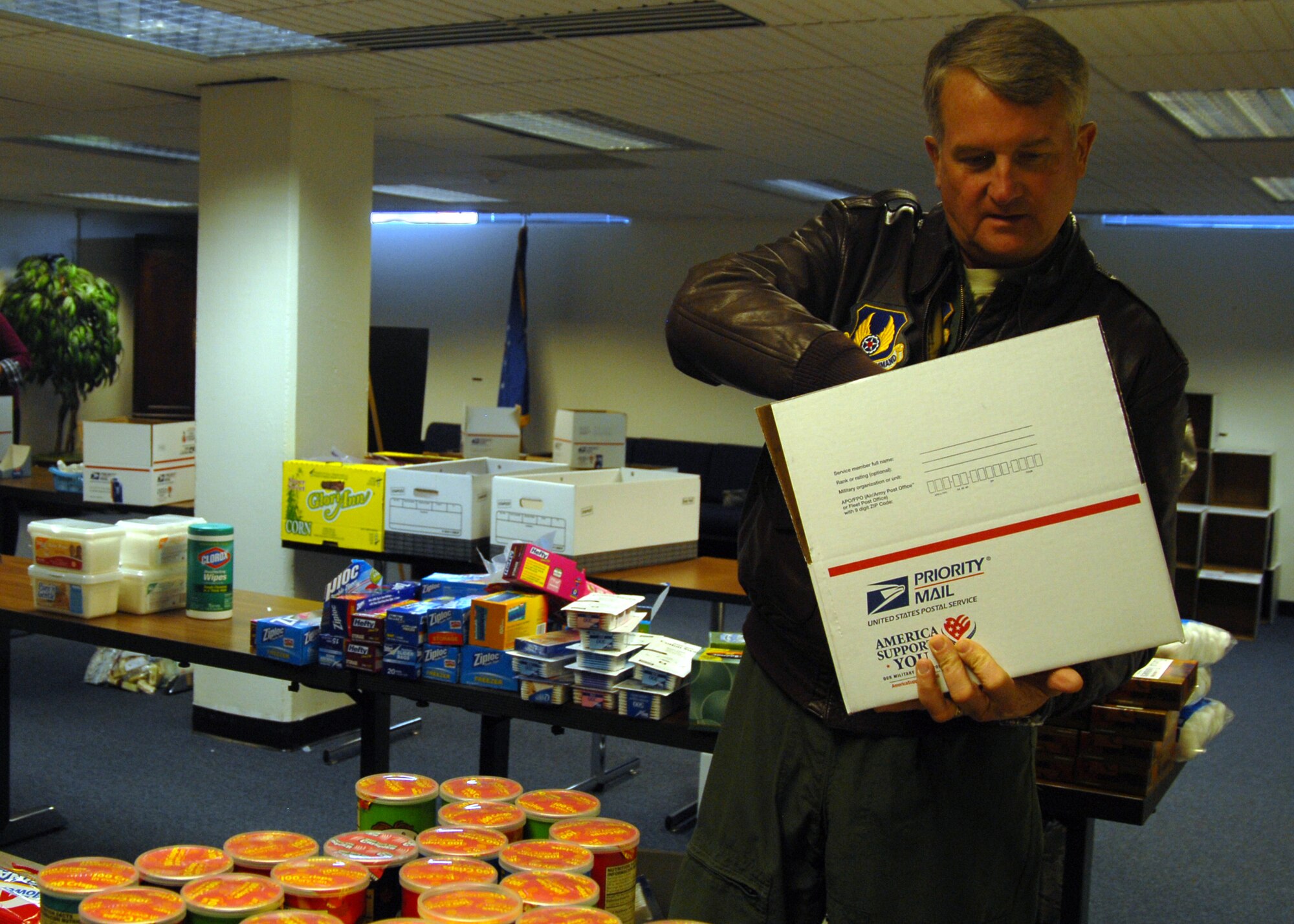 Maj. Gen. David Eichhorn, Air Force Flight Test Center commander, fills a care package with various items Dec. 4 at the First Term Airman Center classroom as part of Operation Touch Our Warriors. Team Edwards collected and donated care package items as gifts to deployed troops. (U.S. Air Force photo/Senior Airman Julius Delos Reyes)
