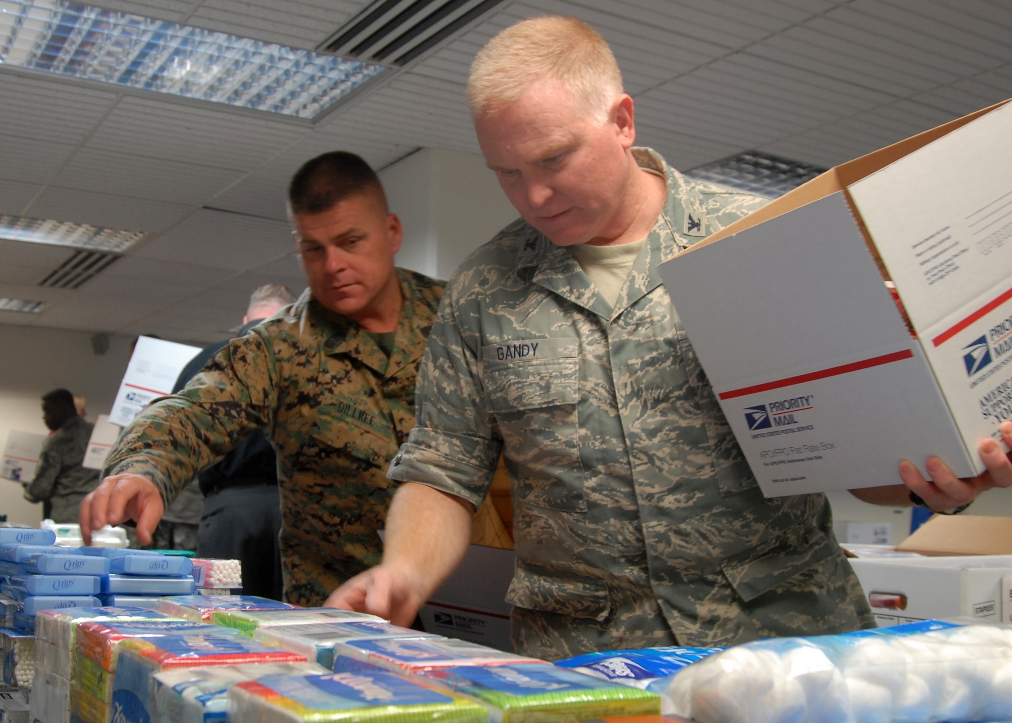 Col. Jerry Gandy (right), 95th Air Base Wing commander, and Marine Sgt. Maj. Charles Dillree, Marine Aircraft Group 46 Detachment Bravo sergeant major, pack care packages Dec. 4 at the First Term Airman Center classroom as part of Operation Touch our Warriors. (U.S. Air Force photo/Senior Airman Julius Delos Reyes)