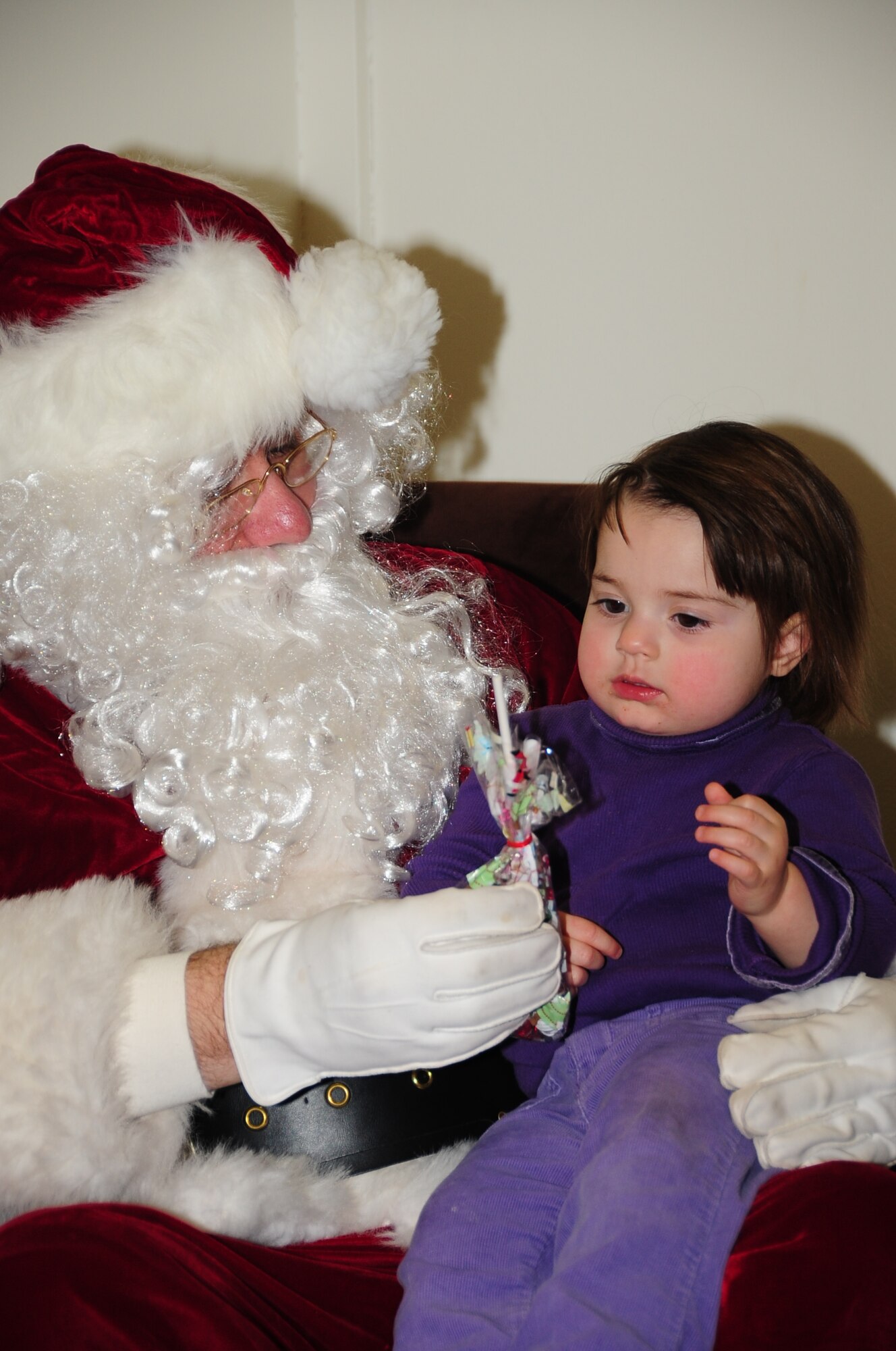 ELLSWORTH AIR FORCE BASE, S.D. -- Mary Isabel Traynor, daughter of Maj. Patricia Traynor, 28th Bomb Wing Staff chief of public affairs, sits on Santa's lap and receives a small bag of candy, Dec. 3.  During the annual tree-lighting ceremony, the combined chapel choir sang Christmas songs as the tree was lit. (U.S. Air Force photo/Airman 1st Class Anthony Sanchelli)