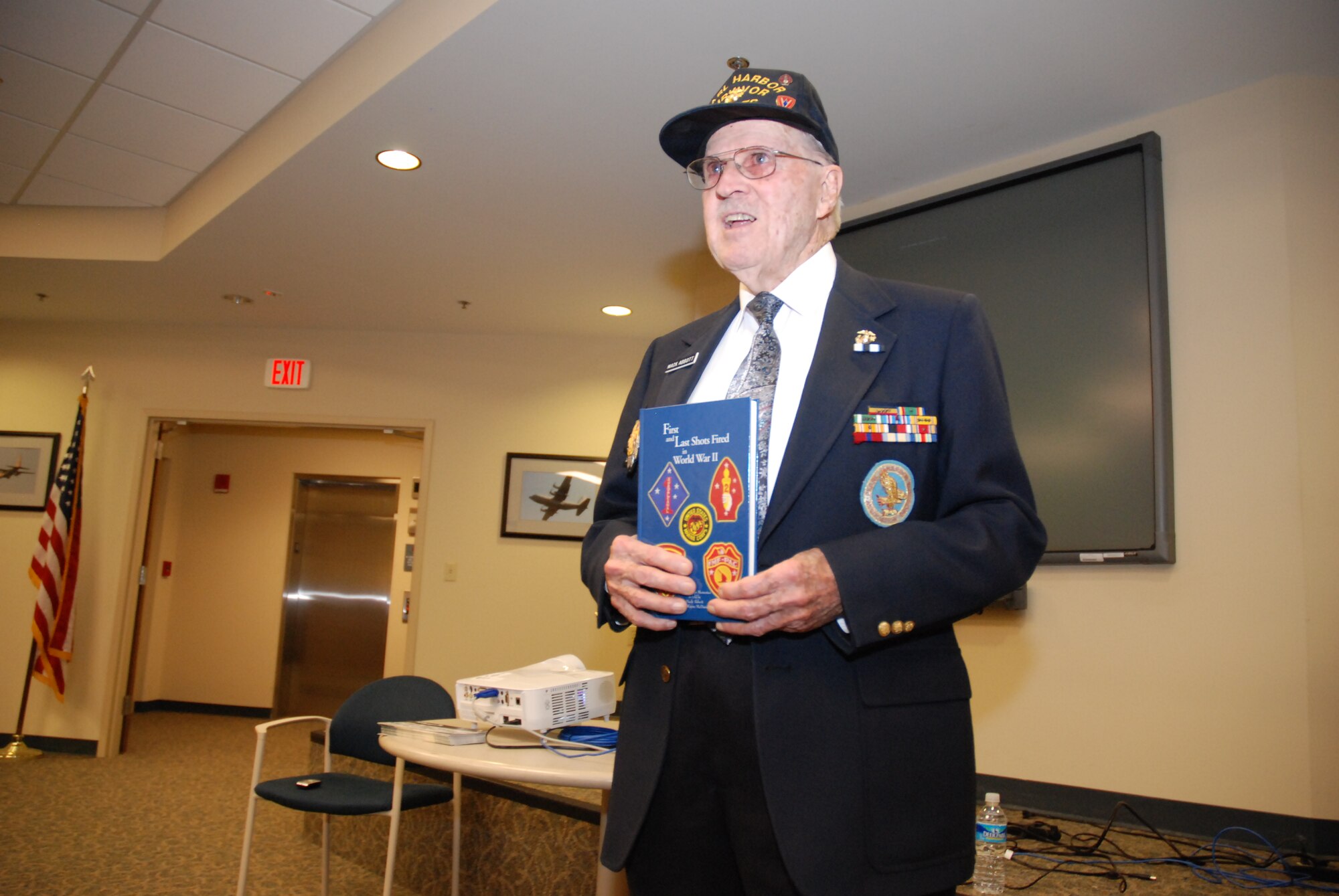 Mr. Abbott presents his book—“First and Last Shots Fired in World War II”—to the audience regarding his experiences in the Pacific Theater in the war with Japan.  
(U.S. Air Force photo/Master Sgt. Stan Coleman)

