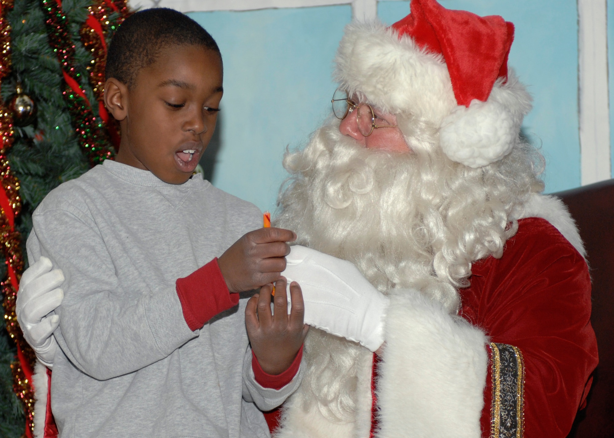 CANNON AIR FORCE BASE, N.M.--Santa Clause hands Matthew Moore a candy cane while he listens to him at The Drop Zone Dec. 5. Santa and his wife plan on making a special appearance at the Deployed/Remote Spouses Dinner at the dinning facility Dec. 8.  (U.S. Air Force Photo by Senior Airmen James Bell)