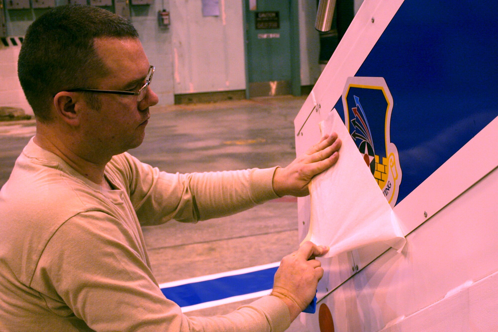 GRISSOM AIR RESERVE BASE, Ind., -- Tech. Sgt. Sean Kelly, an aircraft structural maintenance specialist with the 434th Maintenance Squadron, applies a 434th Air Refueling Wing shield decal to the side support at the base of a passenger stairway truck recently acquired for use at Grissom.  (U.S. Air Force photo/Staff Sgt. Chris Bolen)
