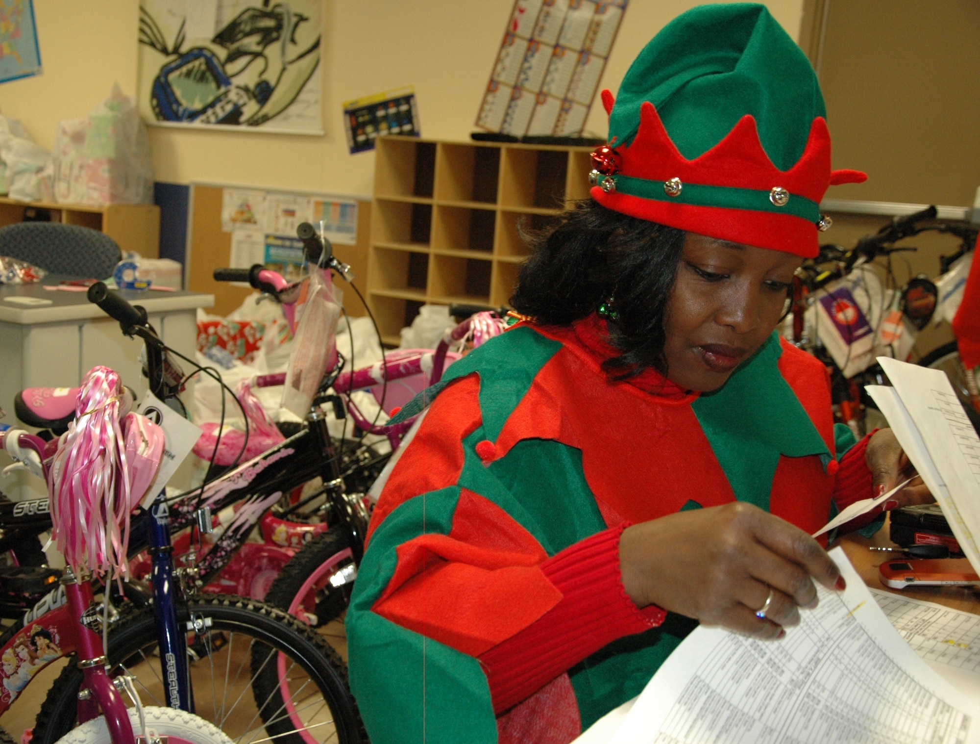 Capt. Rosaline Mailandt-Norris checks the list of presents Santa was about to present during Give a Child a Christmas Dec. 5. The volunteer CGO from the Joint Fires Integration and Interoperability Team lead the coordination of all activities at the Youth Center and said the holiday season is her favorite time of the year. (U.S. Air Force photo by Chrissy Cuttita)