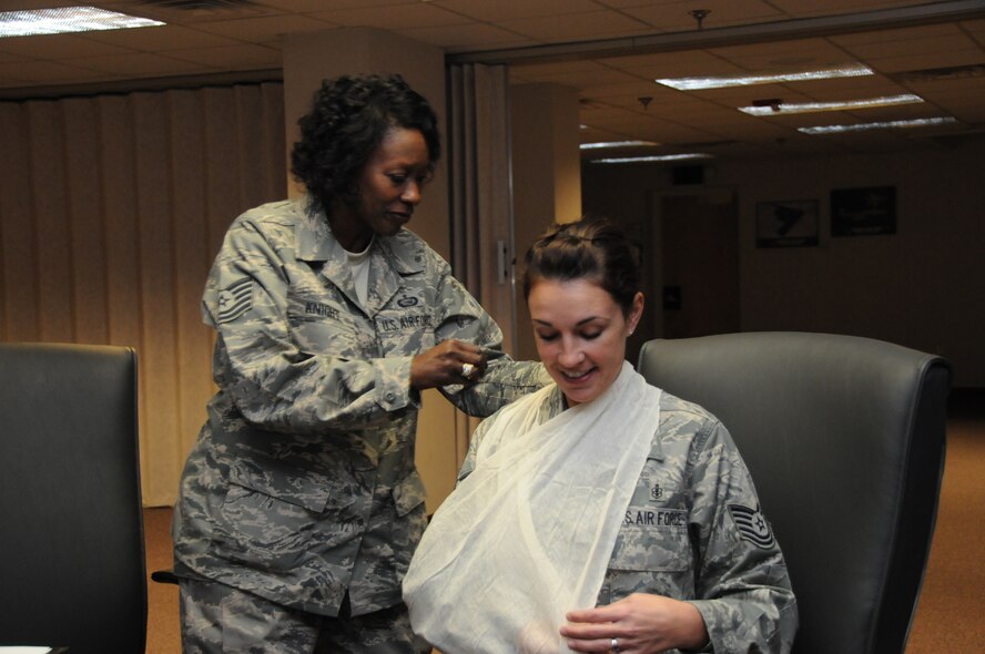 Tech. Sgt. Lavonia Knight (left) applies a sling to Tech. Sgt. Sarah Ellen during an instructor training course for Self Aid and Buddy Care at the 916th Air Refueling Wing, Air Force Reserve. (U.S. Air Force photo by: TSgt. Scotty Sweatt, 916ARW/PA)