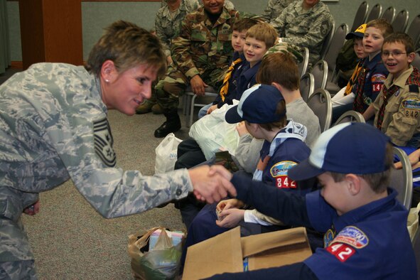 WRIGHT-PATTERSON AIR FORCE BASE, Ohio - 445th Airlift Wing Command Chief Master Sgt. Peri Rogowski “coins” a Cub Scout after accepting a donation of personal care items collected by the Scouts of Pack 842 for the residents of the Veterans Affairs Medical Center, Dayton, Ohio, Dec. 5.  The Scouts, from Lebanon, Ohio, collected the items from neighbors as a community outreach project. The wing delivered the items, along with other personal care items donated by members of the wing, to the residents later that morning.  After being coined by the Command Chief and receiving a huge “thank-you” from the 445th AW commander, Col. Stephen Goeman, the Scouts were treated to a visit on the flight line and toured a C-5 Galaxy. (U.S. Air Force photo/Captain Rodney McNany)