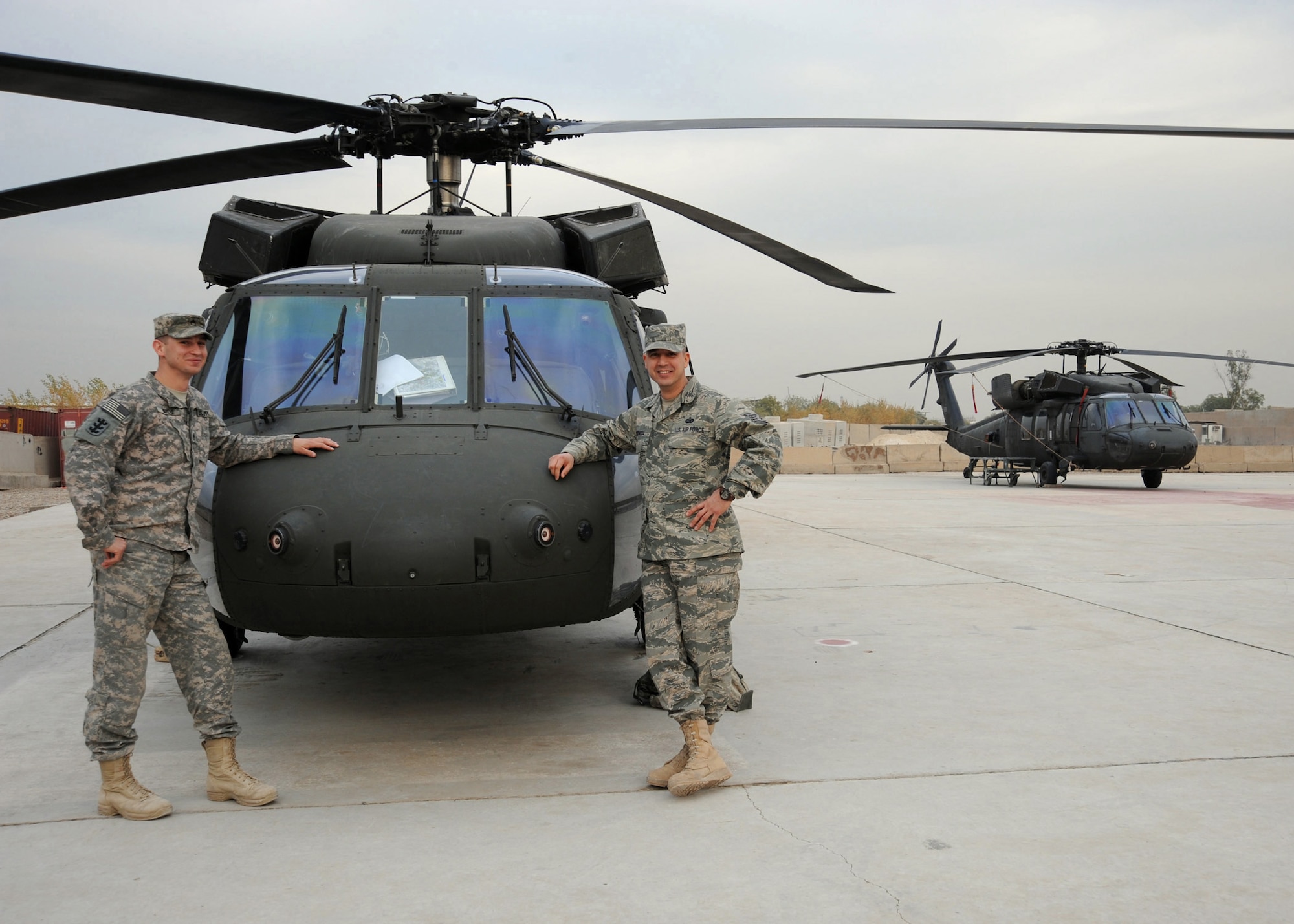 CAMP VICTORY, Iraq -- Army Staff Sgt. James Wardle (left) and Air Force Tech. Sgt. Jeffrey Kidwell, administrative and operations noncommissioned officers for  Multinational Corps-Iraq senior leaders, pose in front of the UH-60 Blackhawk that provides transportation for their bosses throughout Iraq Dec. 5, 2009. They are responsible for coordinating the planning stages of the mission in order to support operations and get to where they need to go.  Sergeant Kidwell is deployed from Barksdale Air Force Base, La., and hails from Alamogordo, N.M., and Sergeant Wardle is deployed from Fort Lewis, Wash., and is a native of Boise, Idaho. (U.S. Air Force photo/Master Sgt. Trish Bunting)