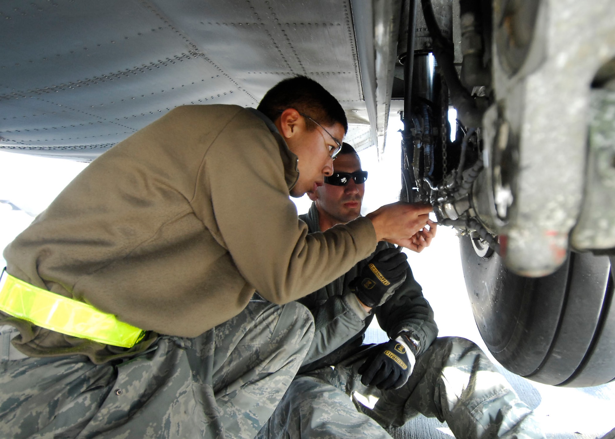 BAGRAM AIRFIELD, Afghanistan -- Senior Airman Elliroy Defiesta (left) assists Tech. Sgt. Mike Smith (right) while performing landing gear maintenance on a C-130 Hercules, Dec. 7, 2009.  During an inspection on the aircraft the Airmen found a problem with the landing gear which they immediately fixed to keep the aircraft on time for future missions.  Both Airmen, crew chiefs from the 455th Expeditionary Aircraft Maintenance Squadron, are deployed from the Nevada Air National Guard's 152nd Airlift Wing and hail from Reno, Nev.  (U.S. Air Force photo/Senior Airman Felicia Juenke)