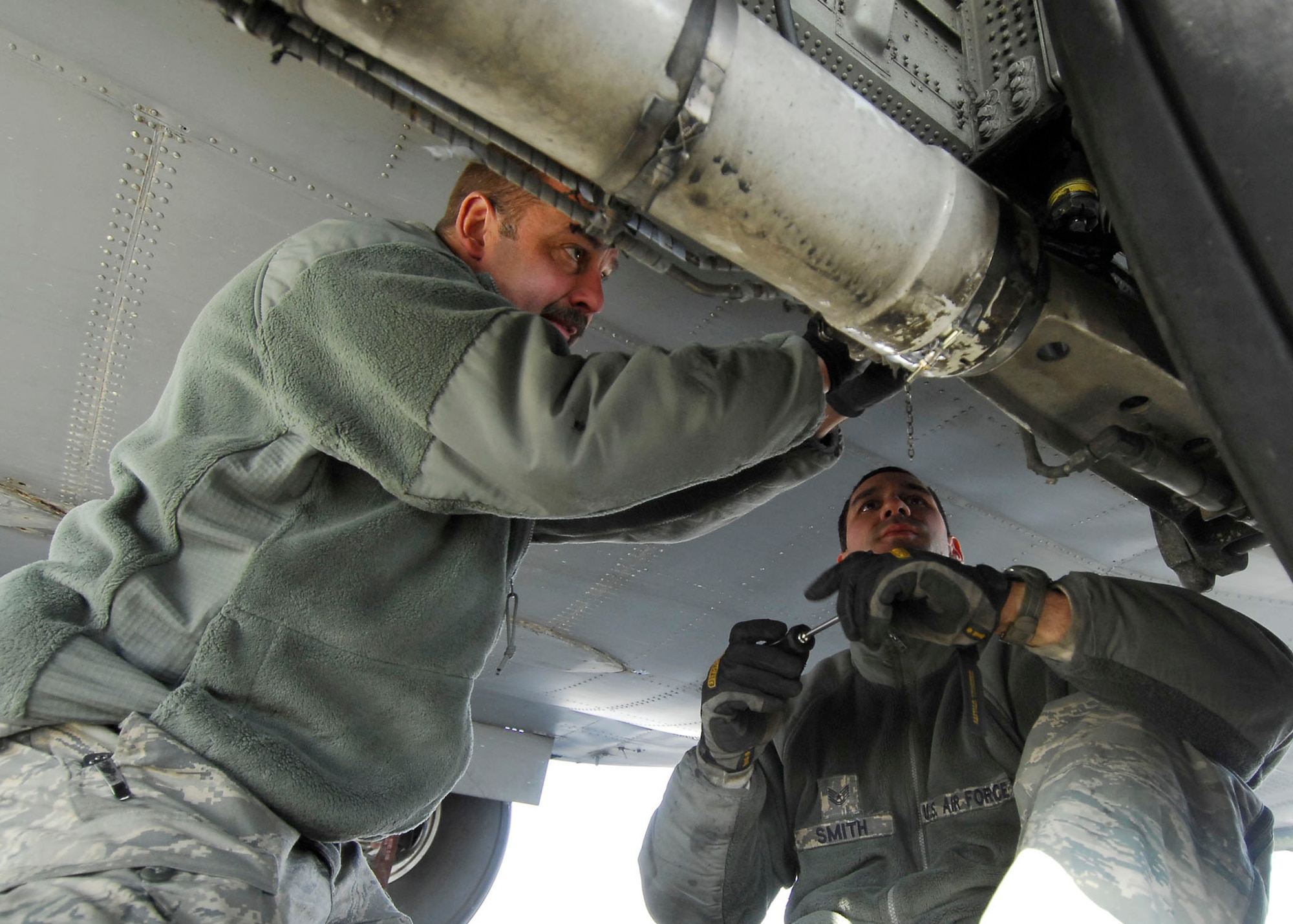 BAGRAM AIRFIELD, Afghanistan -- Master Sgt. Jim Kocijanski (left) assists Tech. Sgt. Mike Smith (right) while performing landing gear maintenance on a C-130 Hercules, Dec. 7, 2009.  During an inspection on the aircraft the Airmen found a problem with the landing gear which they immediately fixed to keep the aircraft on time for future missions.  Both Airmen, crew chiefs from the 455th Expeditionary Aircraft Maintenance Squadron, are deployed from the Nevada Air National Guard's 152nd Airlift Wing and hail from Reno, Nev.  (U.S. Air Force photo/Senior Airman Felicia Juenke)