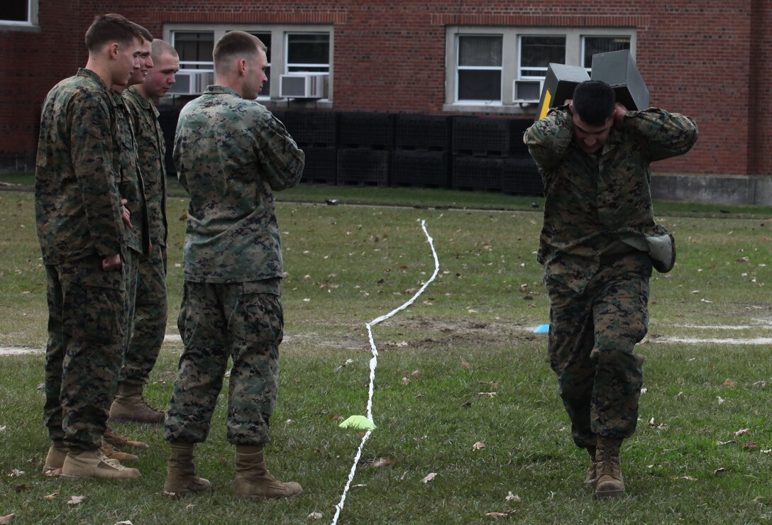 Marine Corps Base Camp Lejeune - Marines attending the Combat Fitness Training course look on as Staff Sgt. Sandoval Eric M., a platoon sergeant for guns platoon, Battery G, 2nd Battalion, 10th Marine Regiment, 2nd Marine Division demonstrates on of the many ways to carry ammunition cans while conducting the combat fitness test.