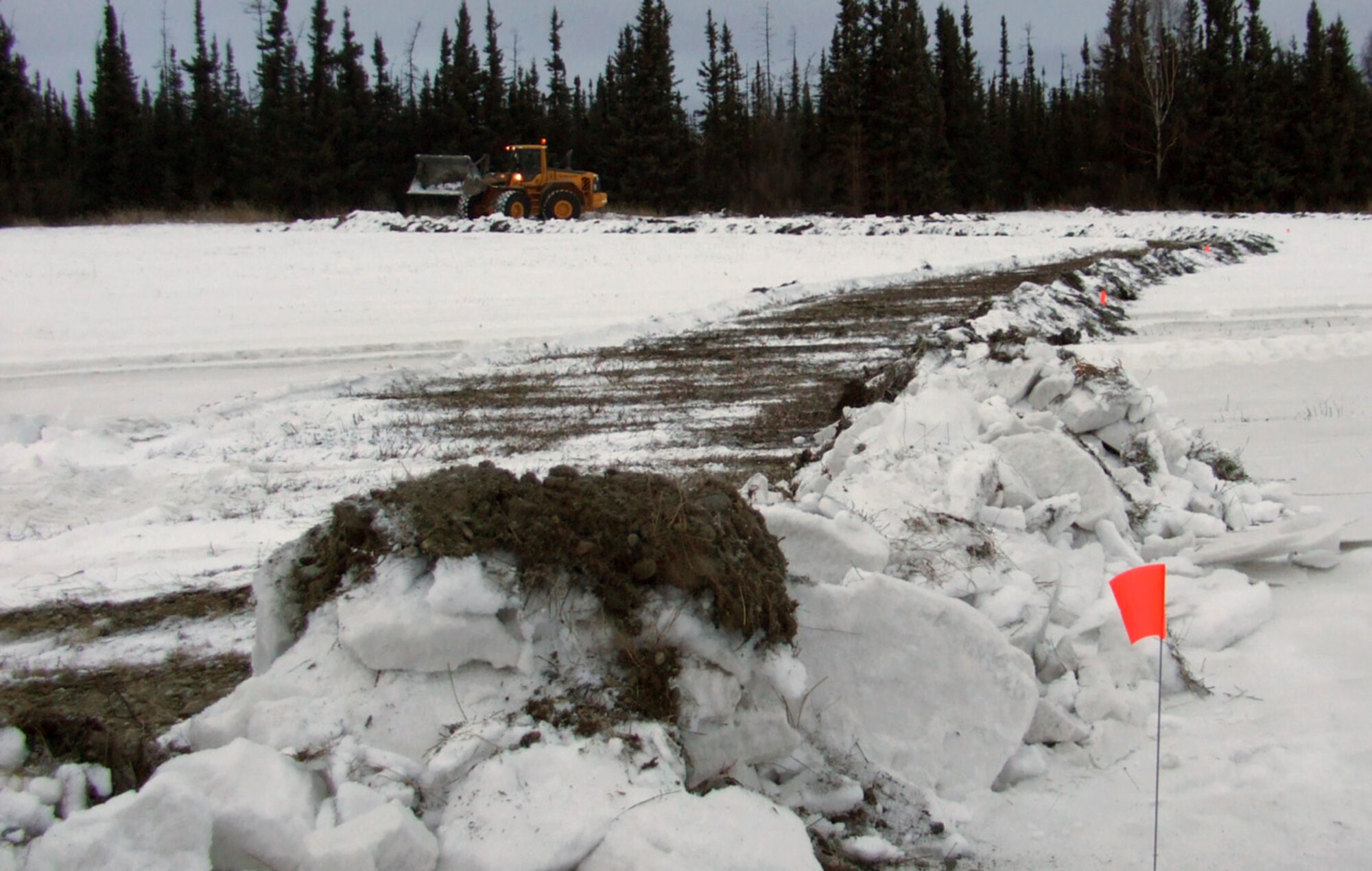 A front loader, with the 354th Civil Engineer Squadron's horizontal construction flight, uses snow to build a secondary containment area for a simulated oil spill during an Emergency Management Exercise Dec. 3, Eielson Air Force Base, Alaska. The exercise evaluated the capabilities of responders and base leadership in response to a major spill. (U.S. Air Force courtesy photo)
