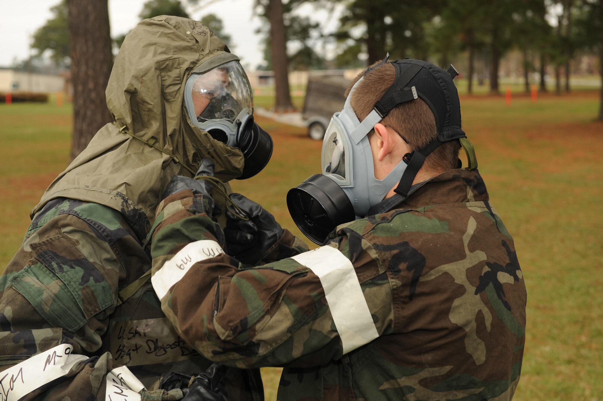 Airman Joshua Walk (right), assists Staff Sgt. Douglas D'Agostino, both from the 4th Aircraft Maintenance Squadron, in taking off his mask hood at the contamination control area on Seymour Johnson Air Force Base, N.C., Dec. 7, 2009. The buddy system is used when completing decontamination tasks so contamination doesn't spread when removing equipment. (U.S. Air Force photo/Senior Airman Ciara Wymbs) 